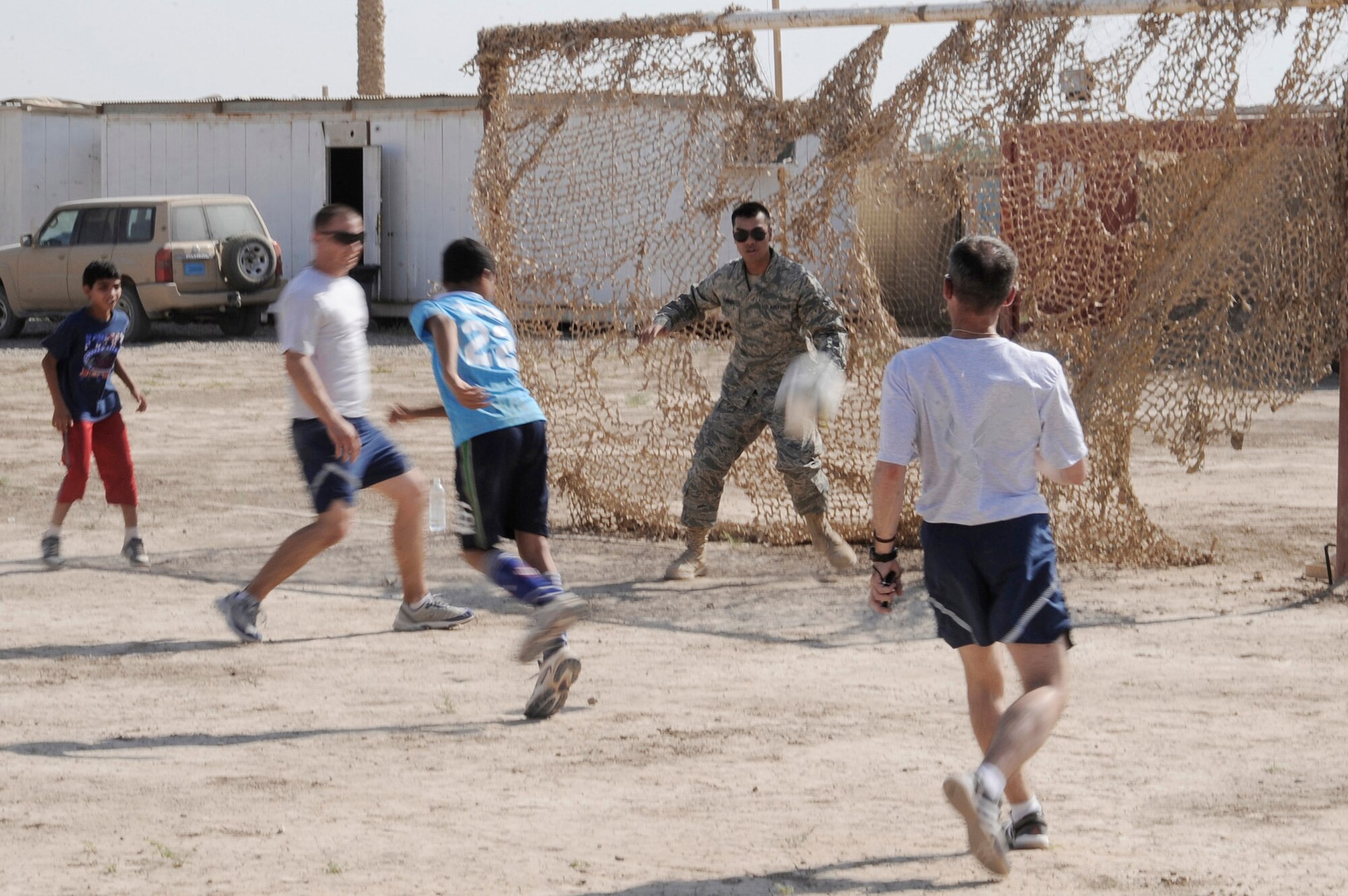 Airman 1st Class Tyrone Flores plays goalie against local Iraqi children and fellow Air Force members July 24 in Baghdad. Forty-five Airmen and Soldiers volunteered to visit and distribute donated items to local Iraqi families as part of the Sather Air Base Good Neighbor Program. Airman Flores is a Multinational Corps-Iraq server room technician. Airman Flores is deployed from Ramstein Air Base, Germany, and is a native of San Bruno, Calif. (U.S. Air Force photo/Tech. Sgt. Johnny L. Saldivar)
