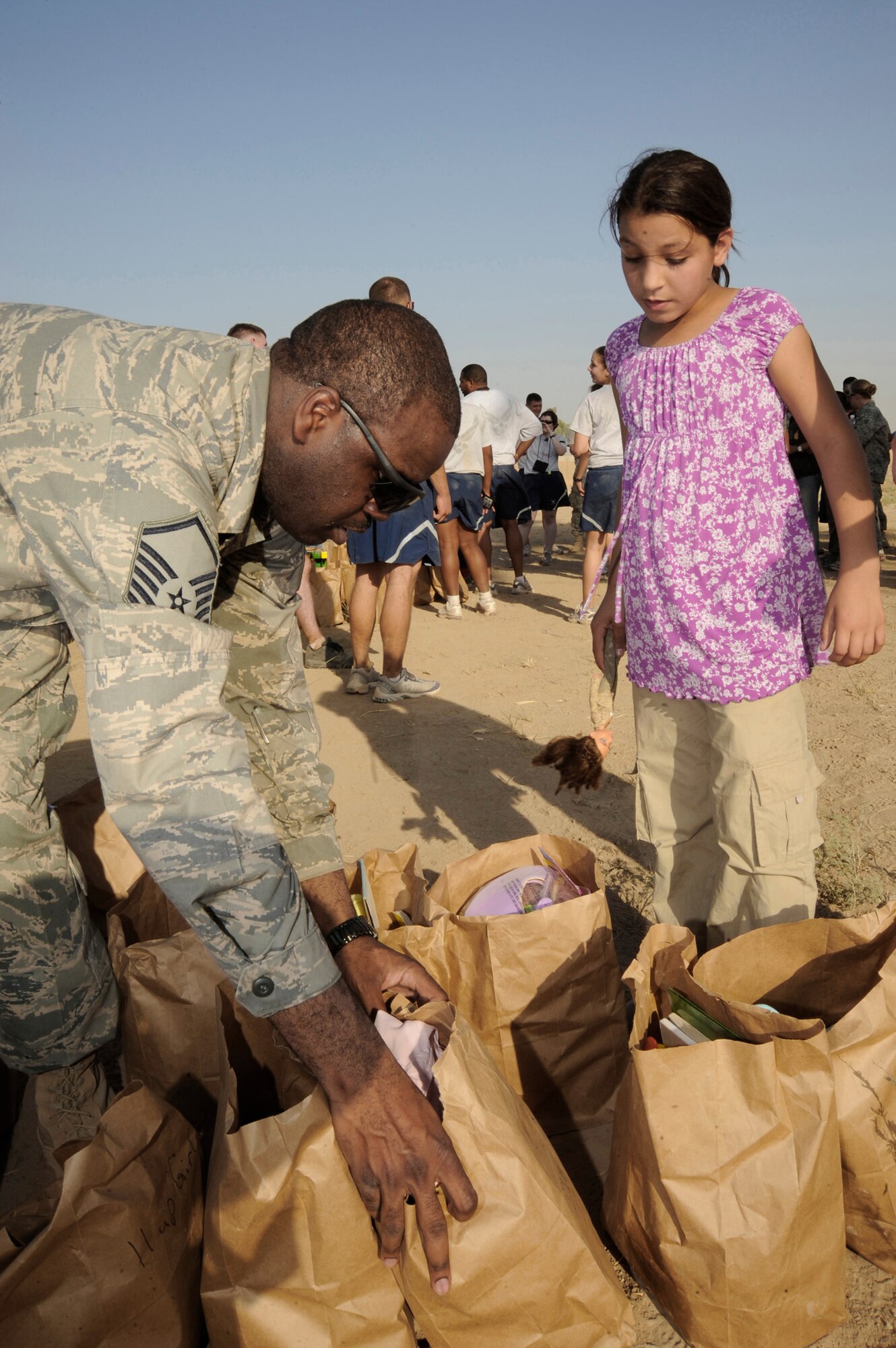 Master Sgt. Shantell Frierson prepares to hand a bag full of donations to an Iraqi girl July 24 in Baghdad. Sergeant Frierson is a Multinational Corps-Iraq Joint Crew Composite Squadron automated data processing technician. Sergeant Frierson is deployed from Ramstein Air Base, Germany, and is a native of Coward, S.C. (U.S. Air Force photo/Tech. Sgt. Johnny L. Saldivar) 