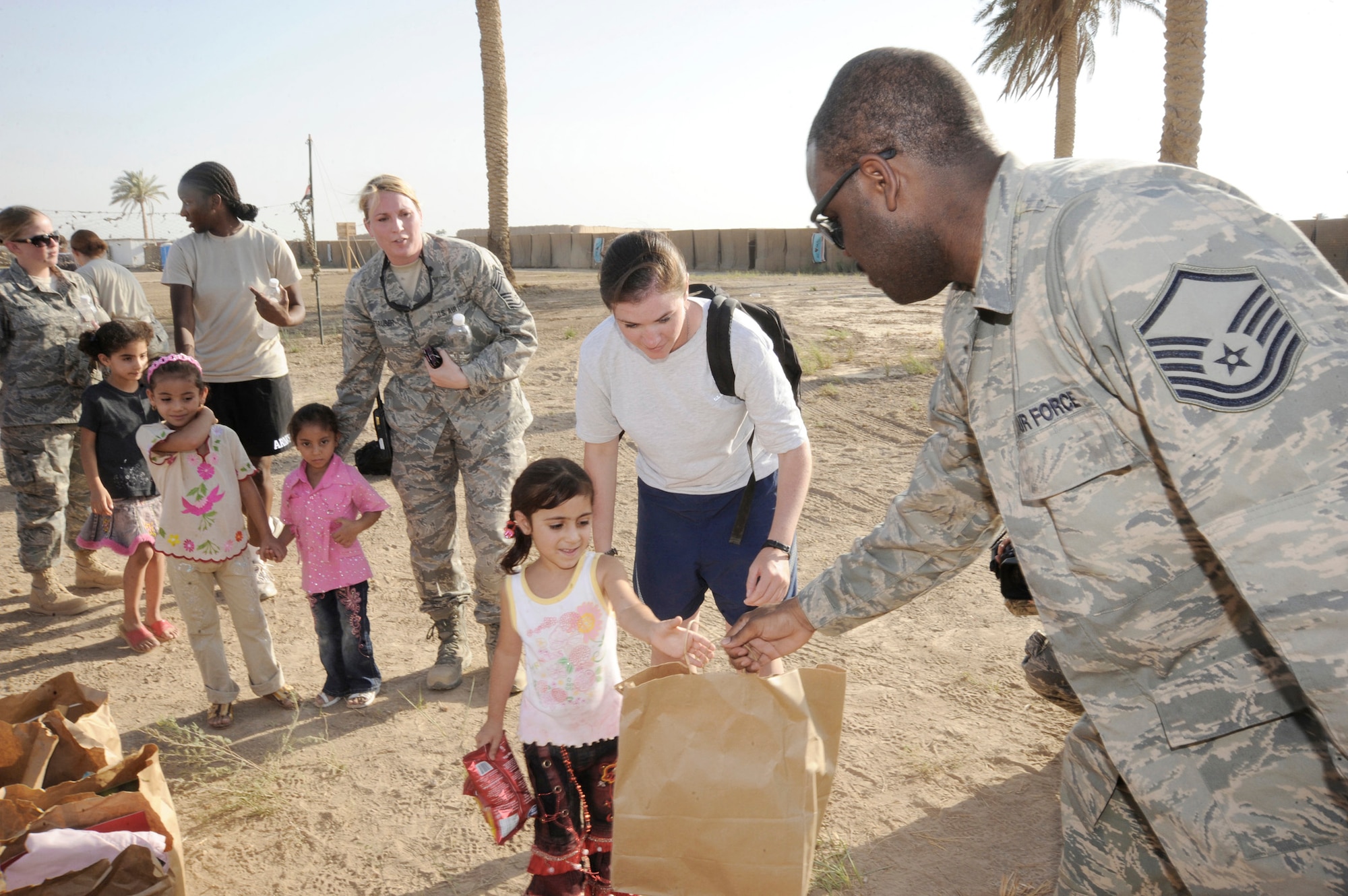 Master Sgt. Shantell Frierson hands an Iraqi child a bag of treats July 24 in Baghdad. Forty-five Airmen and Soldiers volunteered to visit and distribute donated items to local Iraqi families as part of the Sather Air Base Good Neighbor Program. Sergeant Frierson is a Multinational Corps Iraq Joint Crew Composite Squadron automated data processing technician. Sergeant Frierson is deployed from Ramstein Air Base, Germany, and is a native of Coward, S.C. (U.S. Air Force photo/Tech. Sgt. Johnny L. Saldivar)