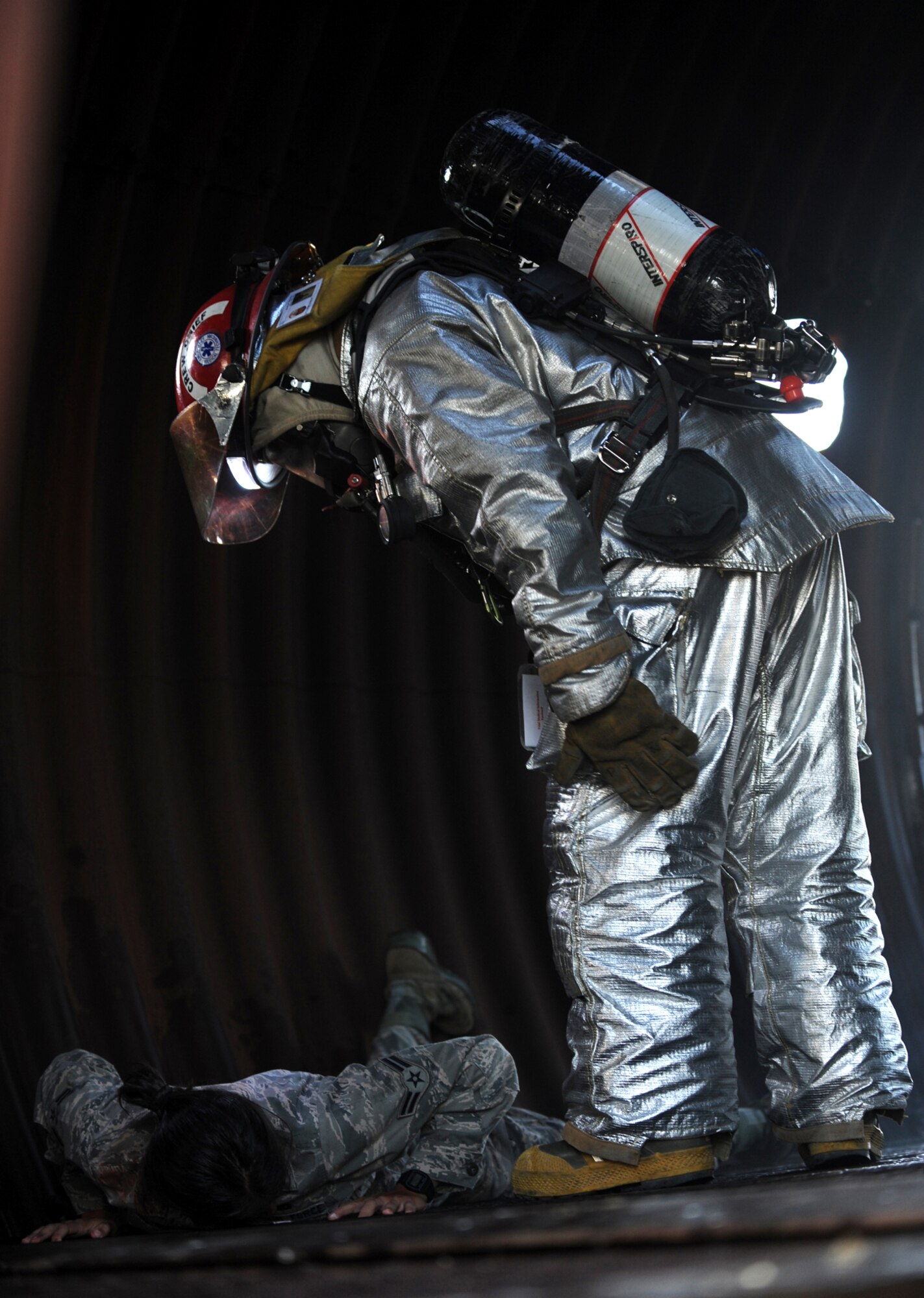 HOLLOMAN AIR FORCE BASE, N.M. -- A member of the Holloman Fire Emergency Services checks for consciousness in a simulated casualty during the Major Accident Response Exercise here July 23. Role-players were used to make the scenario realistic and to exercise the emergency phase of the exercise. After performing triage of the victims, they were removed from the artificial aircraft and transported to a safe distance away from the aircraft. (U.S. Air Force photo by Airman 1st Class Sondra M. Escutia)