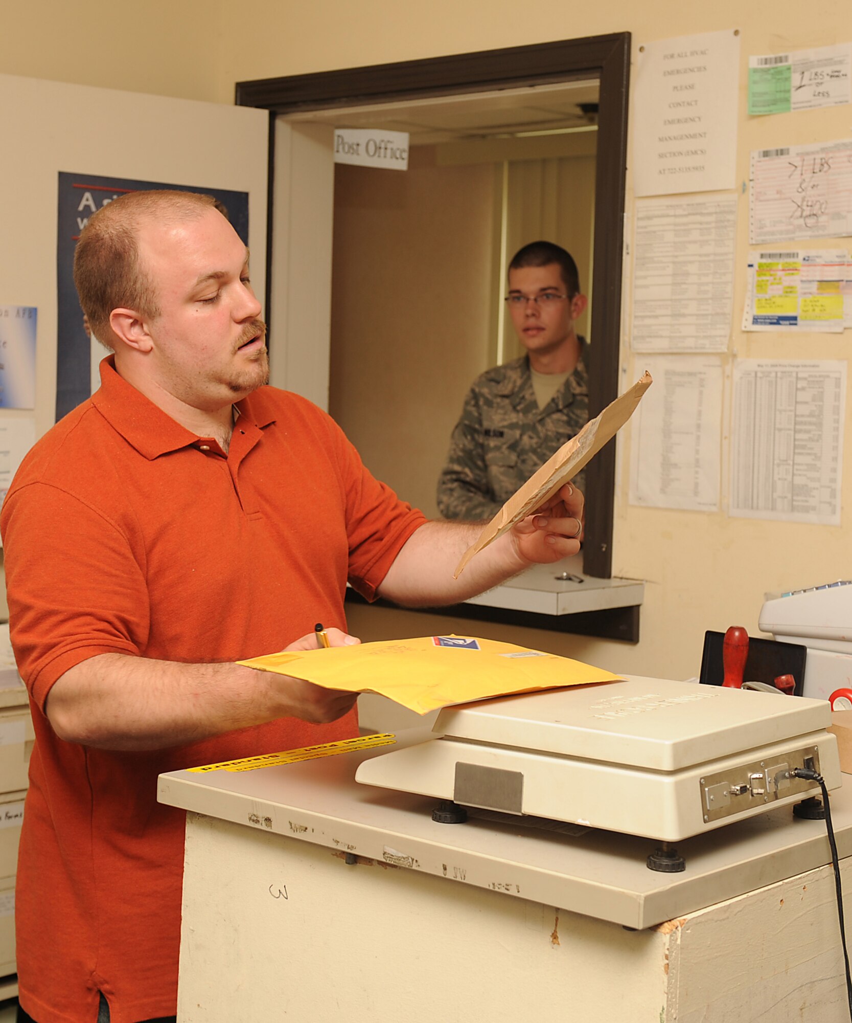 David Medus, U.S. Postal Service clerk, assists Airman Joshua Wilson, 4th Component Maintenance Squadron egress systems apprentice, in shipping packages at Seymour Johnson Air Force Base, N.C., July 24, 2009. The base post office receives approximately 800 packages and 1,500 letters weekly. (U.S. Air Force photo by Airman 1st Class Whitney S. Lambert)