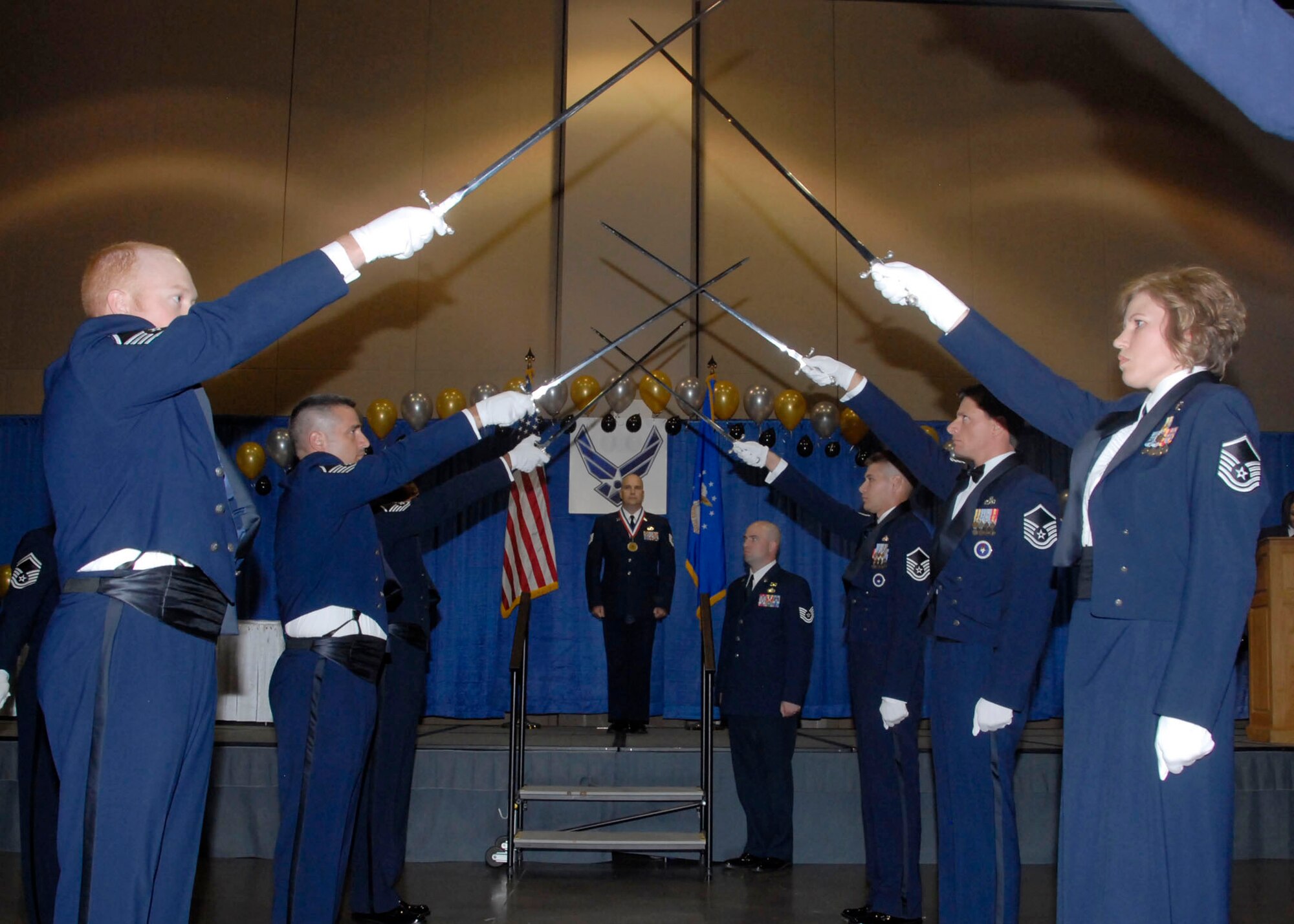 A cordon of master sergeants hold their swords in an arch as master sergeant selects pass underneath during the Senior NCO Induction Ceremony. Eighty-one technical sergeants were inducted to the senior NCO ranks July 24 at the Multi-Purpose Events Center in Wichita Falls. (U.S. Air Force photo/ Mike Litteken)