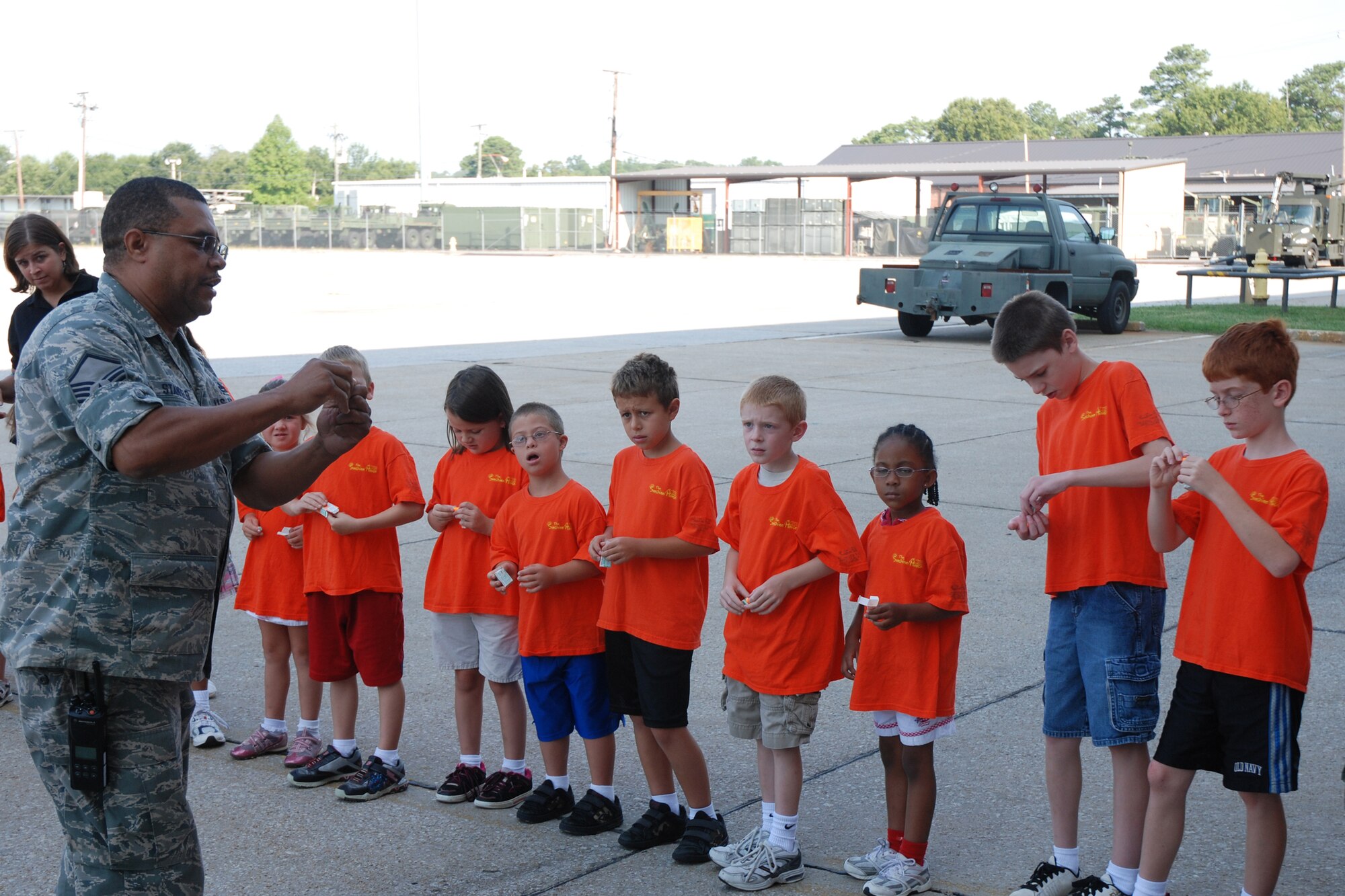 Master Sgt. Floyd Stanfield, 94th Maintenance Group, shows children with the Sunshine House Summer Camp how to insert ear plugs before touring a C-130 aircraft July 28. (U.S. Air Force Photo/Senior Airman Quadoah Ford)