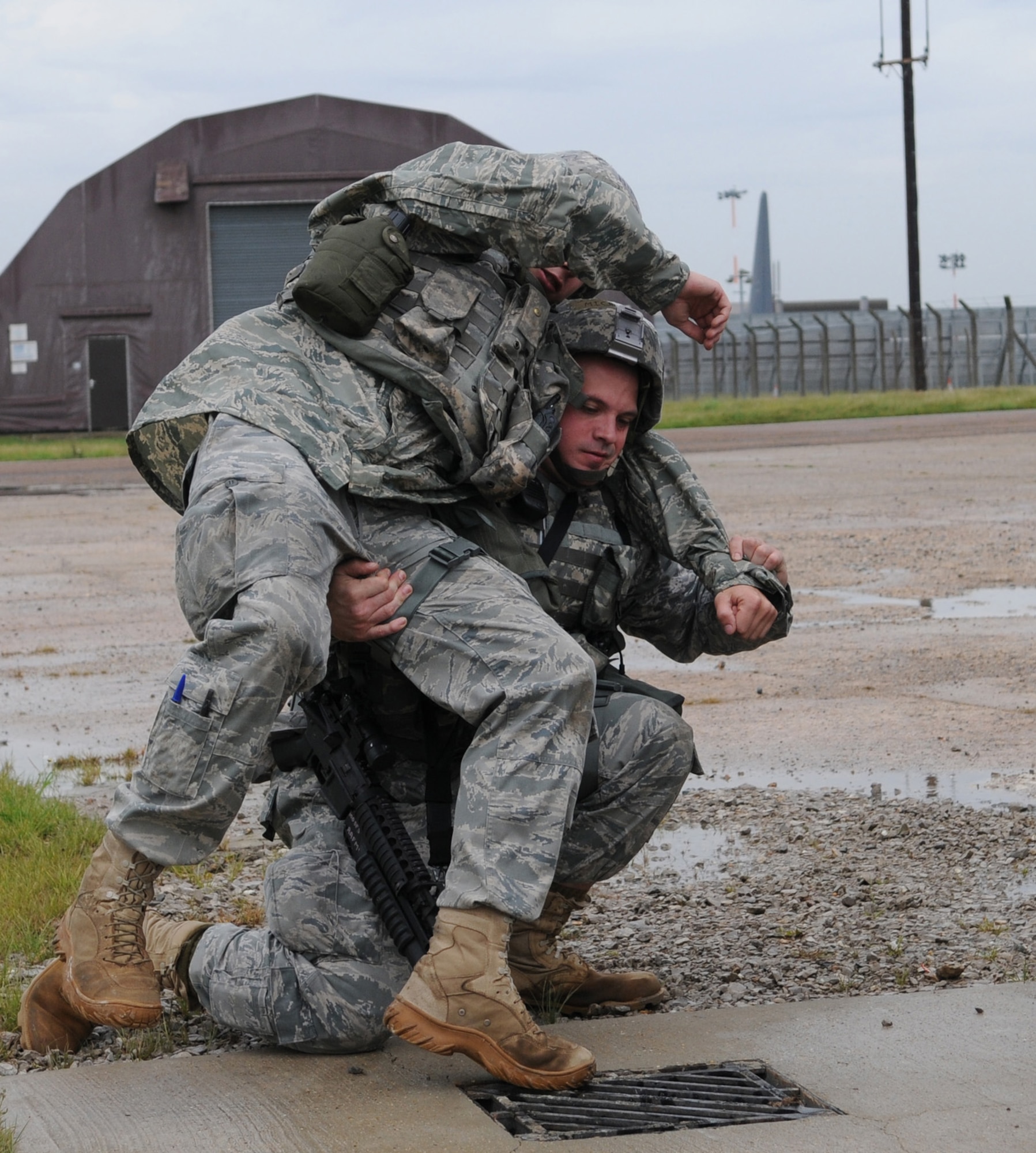 RAF MILDENHALL, England -- Senior Airman Michael Kennedy, of the 100th Secuity Forces Squadron, lifts a “wounded” Airman 1st Class Christopher Eberhardt, also of the 100th SFS, to take shelter from an incoming air attack July 21.  A Phase II exercise was conducted here July 20-22 south of the flightline in preparation for an upcoming Operational Readiness Inspection. (U.S. Air Force photo by Senior Airman Thomas Trower)
