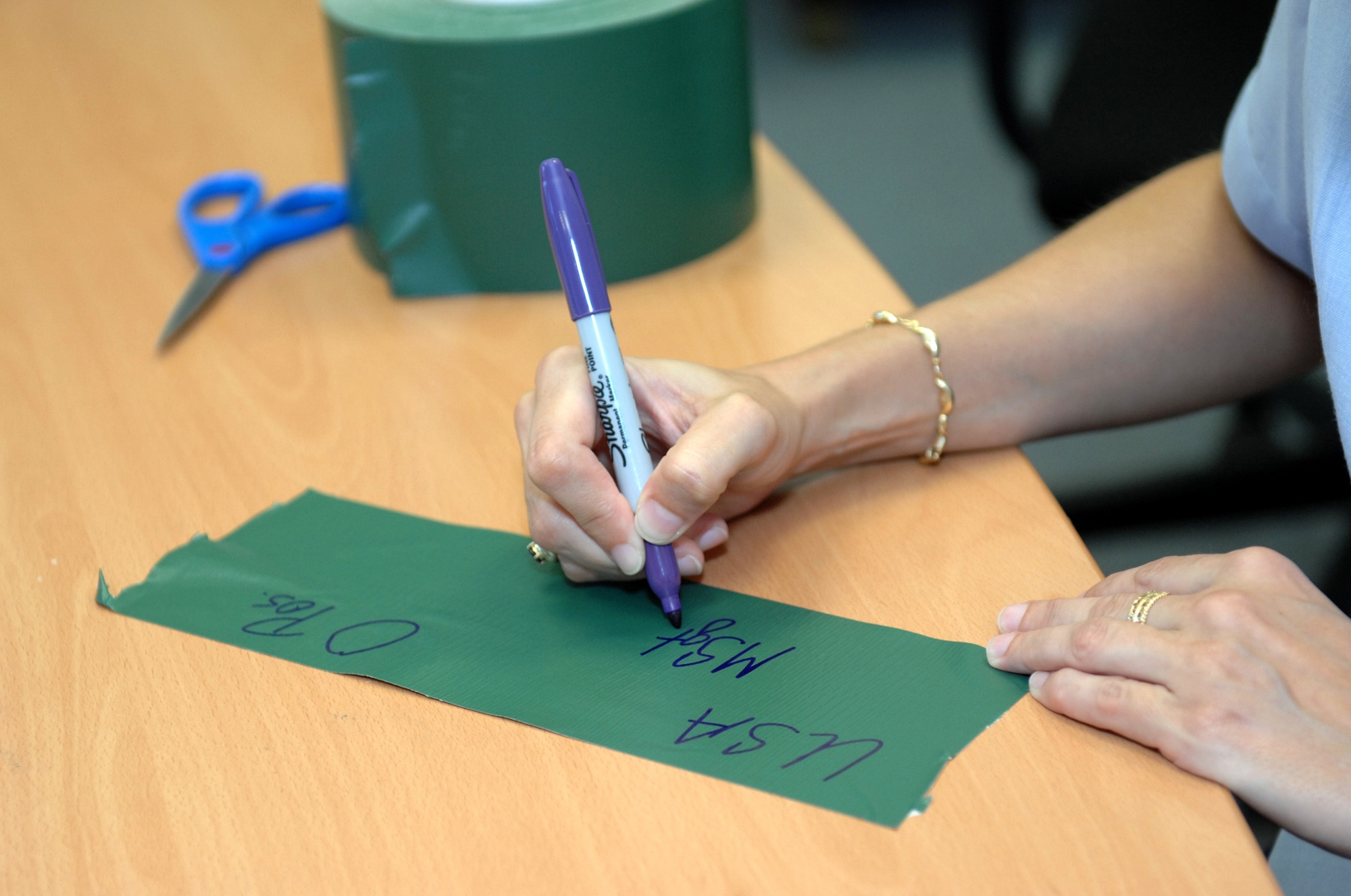 Master Sgt. Kelley Stewart, 52nd Fighter Wing Public Affairs Office, fills out the required information for her chemical gear.  52nd FW members must use NATO markings on their individual protective equipment and chemical gear for the Phase II exercise Aug. 4-7.  The following information needs to be annotated on green duct tape:  first initial, last name; rank; nationality; and blood type.  USA denotes United States of America.  This information must be placed on the front and back of all helmets and hoods, on the jacket over the right side of the chest, and locations indicated in the Airman’s Manual.  (U.S. Air Force photo by Master Sgt. Bill Gomez)