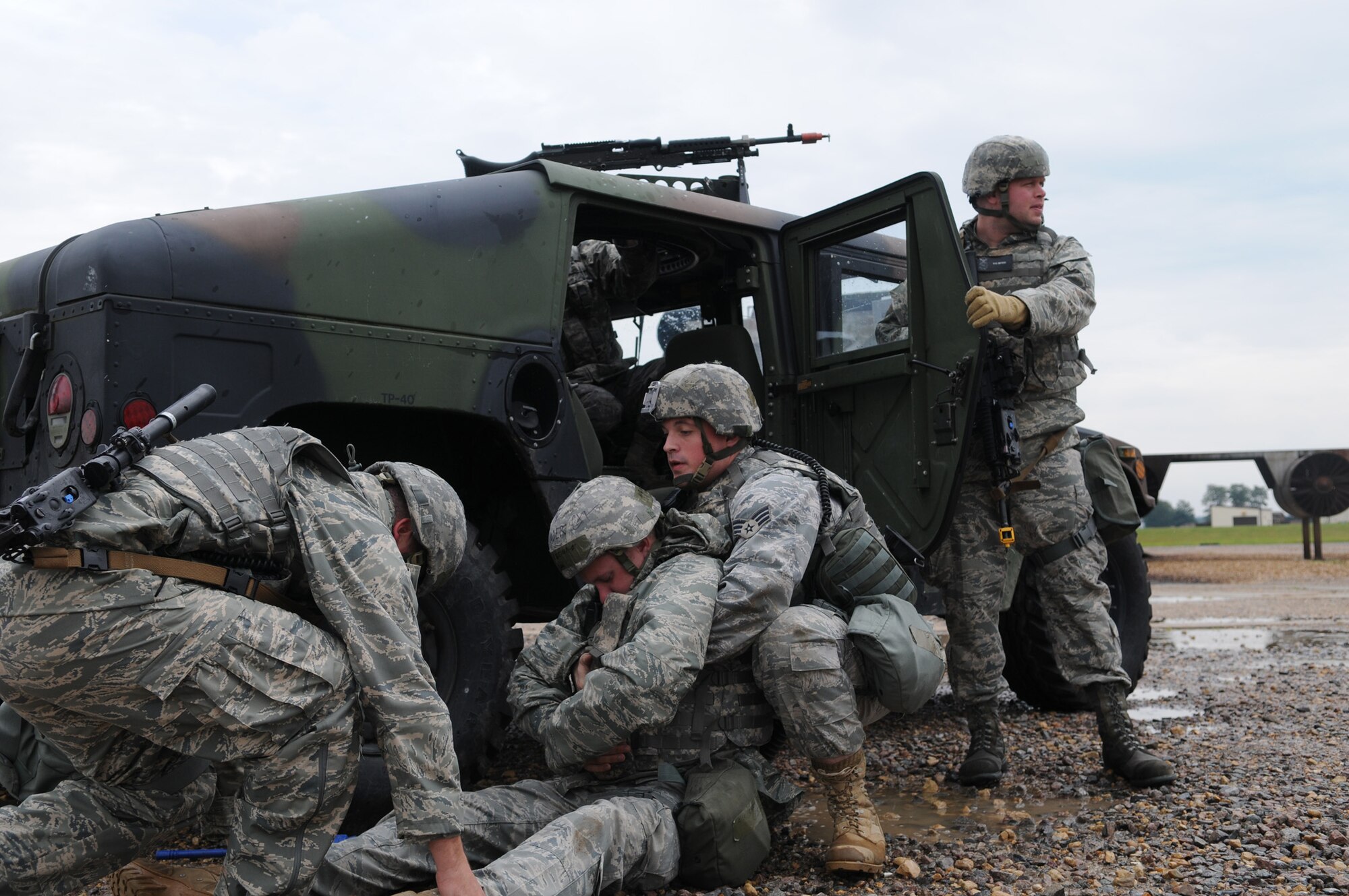 RAF MILDENHALL, England – Senior Airmen Patrick Gorman and Michael Kennedy, both of the 100th Secuity Forces Squadron, lift their “wounded” comrade into the back of their Humvee July 21to take shelter from an incoming air attack.  A Phase II exercise was conducted here July 20-22 south of the flightline in preparation for an upcoming Operational Readiness Inspection. (U.S. Air Force photo by Senior Airman Thomas Trower)