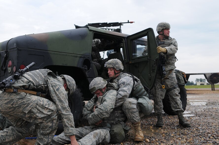 RAF MILDENHALL, England – Senior Airmen Patrick Gorman and Michael Kennedy, both of the 100th Secuity Forces Squadron, lift their “wounded” comrade into the back of their Humvee July 21to take shelter from an incoming air attack.  A Phase II exercise was conducted here July 20-22 south of the flightline in preparation for an upcoming Operational Readiness Inspection. (U.S. Air Force photo by Senior Airman Thomas Trower)