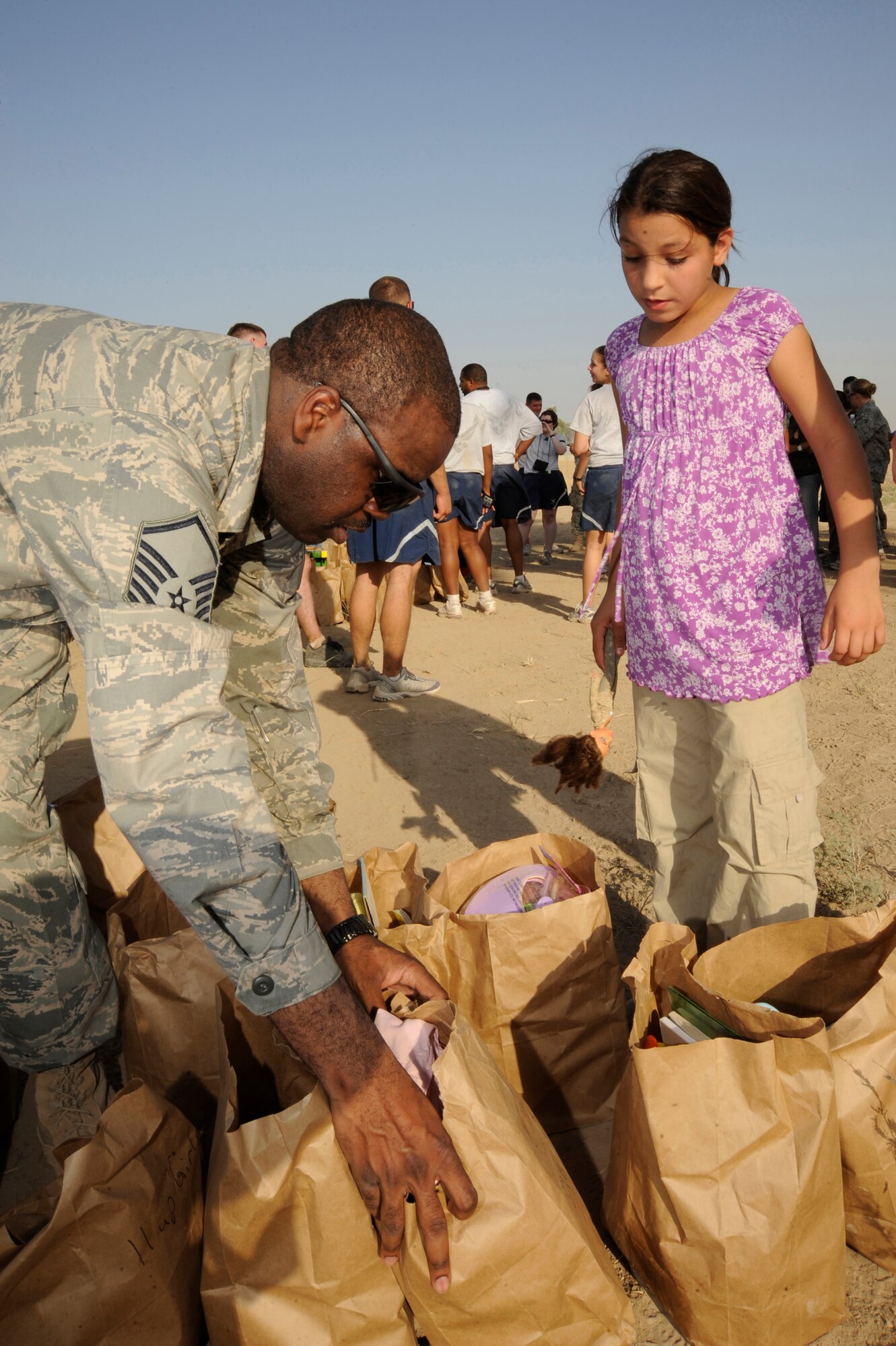 BAGHDAD, Iraq -- Master Sgt. Shantell Frierson, Multi-National Corps Iraq Joint Crew Composite Squadron  automated data processing technician, prepares to hand a bag full of donations to an Iraqi girl here July 24, 2009. Forty-five Airmen and Soldiers volunteered to visit and distribute donated items to local Iraqi families as part of the Sather Air Base Good Neighbor Program. The packages included items the Iraqi families may have had a hard time getting otherwise, such as personal hygiene items, dry food, toys for children, snacks and treats. Sergeant Frierson is deployed from Ramstein Air Base, Germany, and is a native of Coward, S.C.  (U.S. Air Force photo/Tech. Sgt. Johnny L. Saldivar/Released)