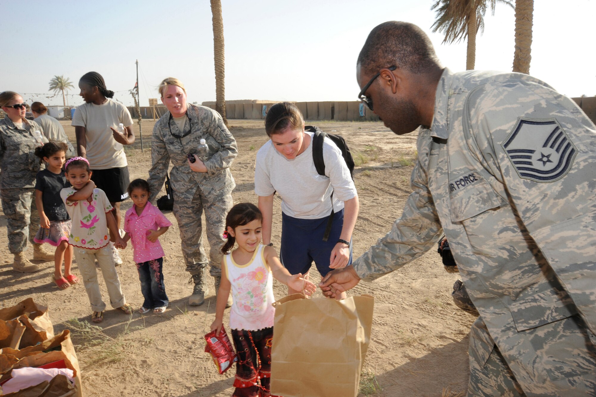 BAGHDAD, Iraq -- Master Sgt. Shantell Frierson, Multi-National Corps Iraq Joint Crew Composite Squadron  automated data processing technician, hands an Iraqi child a bag of treats here July 24, 2009. Forty-five Airmen and Soldiers volunteered to visit and distribute donated items to local Iraqi families as part of the Sather Air Base Good Neighbor Program. The packages included items the Iraqi families may have had a hard time getting otherwise, such as personal hygiene items, dry food, toys for children, snacks and treats. Sergeant Frierson is deployed from Ramstein Air Base, Germany, and is a native of Coward, S.C.  (U.S. Air Force photo/Tech. Sgt. Johnny L. Saldivar/Released)