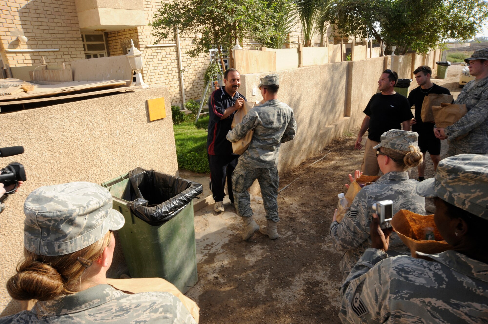 BAGHDAD, Iraq -- Tech. Sgt. Theodore Tetreault, Multi-National Corps Iraq Infrastructure Protection and Reconstruction geo base technician, hands donated items to an Iraqi here July 24, 2009. Forty-five Airmen and Soldiers volunteered to visit and distribute donated items to local Iraqi families as part of the Sather Air Base Good Neighbor Program. The packages included items the Iraqi families may have had a hard time getting otherwise, such as personal hygiene items, dry food, toys for children, snacks and treats. Sergeant Tetreault is deployed from Nellis Air Force Base, Nevada, and is a native of Cape Cod, Mass. (U.S. Air Force photo/Tech. Sgt. Johnny L. Saldivar/Released)