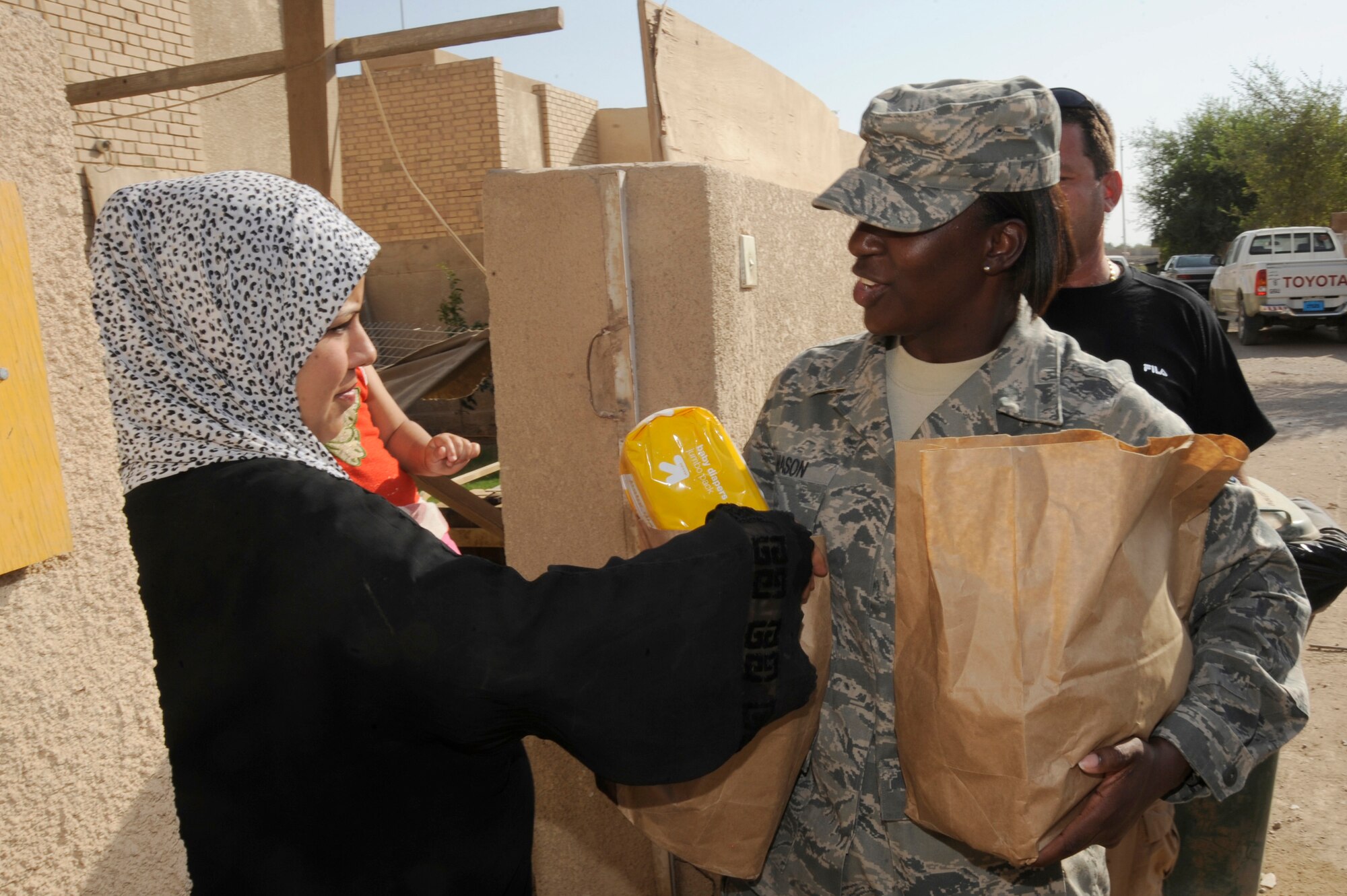 BAGHDAD, Iraq -- Staff Sgt. Shamonn Mason, 447th Expeditionary Force Support Squadron deliberate and crisis action planning and execution segments operator, hands an Iraqi woman donated items for her family here July 24, 2009. Forty-five Airmen and Soldiers volunteered to visit and distribute donated items to local Iraqi families as part of the Sather Air Base Good Neighbor Program. The packages included items the Iraqi families may have had a hard time getting otherwise, such as personal hygiene items, dry food, toys for children, snacks and treats. Sergeant Mason is deployed from Randolph Air Force Base, Texas, and is a native of Morganza, La.  (U.S. Air Force photo/Tech. Sgt. Johnny L. Saldivar/Released)