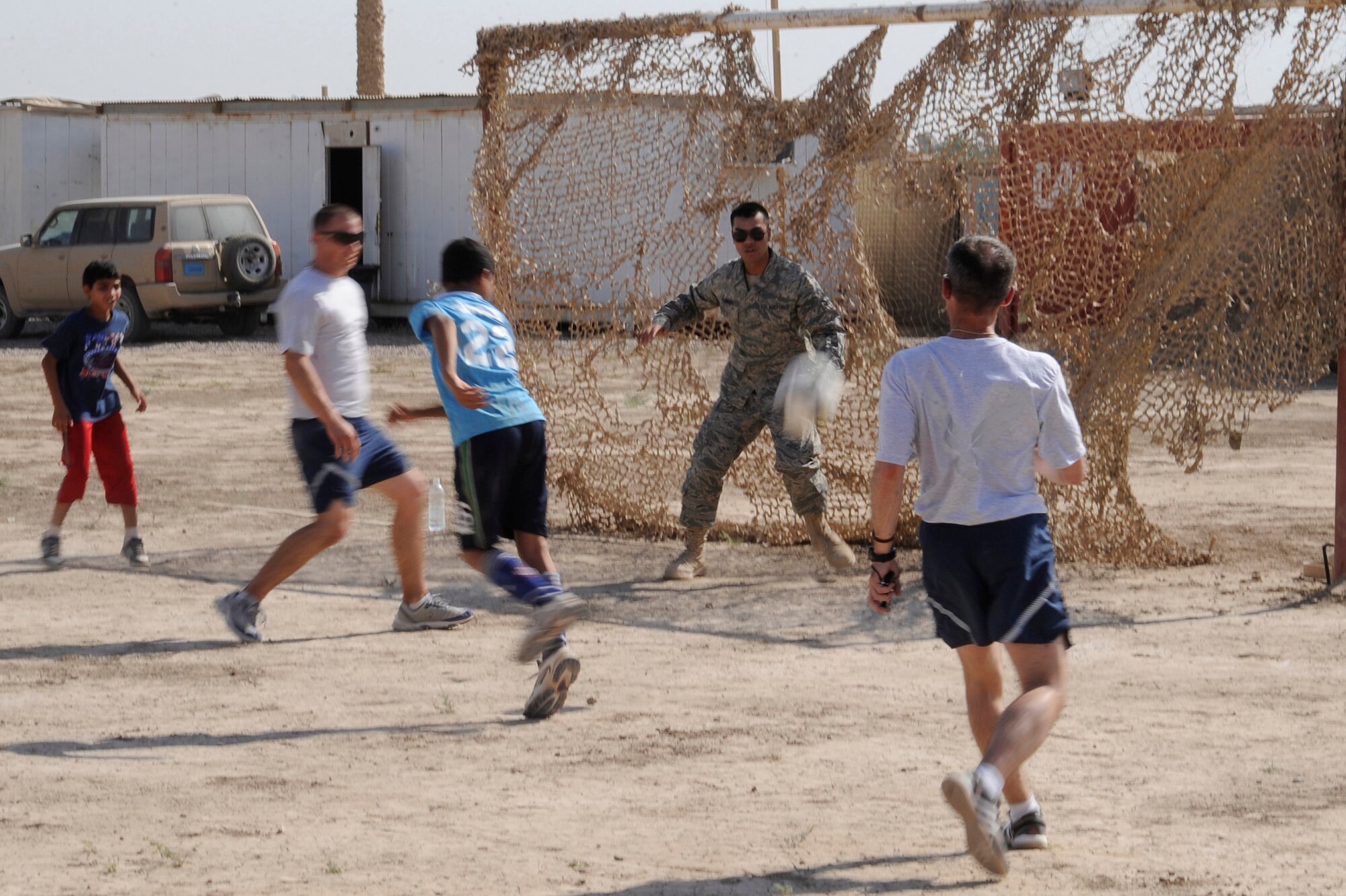 BAGHDAD, Iraq -- Airman 1st Class Tyrone Flores, Multi-National Corps Iraq server room technician, plays goalie against local Iraqi children and fellow Air Force members here July 24, 2009. Forty-five Airmen and Soldiers volunteered to visit and distribute donated items to local Iraqi families as part of the Sather Air Base Good Neighbor Program. The packages included items the Iraqi families may have had a hard time getting otherwise, such as personal hygiene items, dry food, toys for children, snacks and treats. Airman Flores is deployed from Ramstein Air Base, Germany, and is a native of San Bruno, Calif.  (U.S. Air Force photo/Tech. Sgt. Johnny L. Saldivar/Released)
