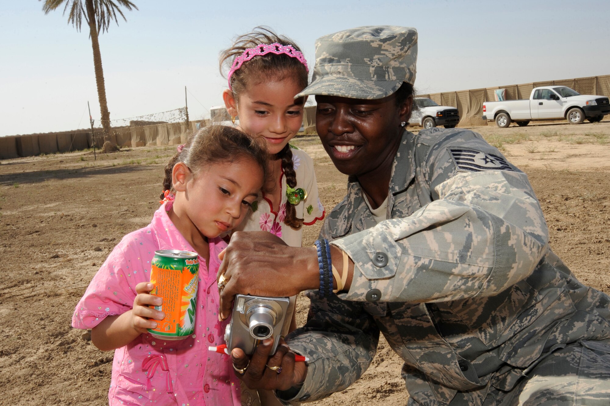 BAGHDAD, Iraq -- Tech. Sgt. Angelyn McKelley, awards and decorations noncommissioned officer in charge for Iraq Training and Advisory Mission-Army, shares photos with Iraqi children here July 24, 2009. Forty-five Airmen and Soldiers volunteered to visit and distribute donated items to local Iraqi families as part of the Sather Air Base Good Neighbor Program. The packages included items the Iraqi families may have had a hard time getting otherwise, such as personal hygiene items, dry food, toys for children, snacks and treats. Sergeant McKelley is deployed from Hill Air Force Base, Utah, and is a native of Carmel, Calif.  (U.S. Air Force photo/Tech. Sgt. Johnny L. Saldivar/Released)
