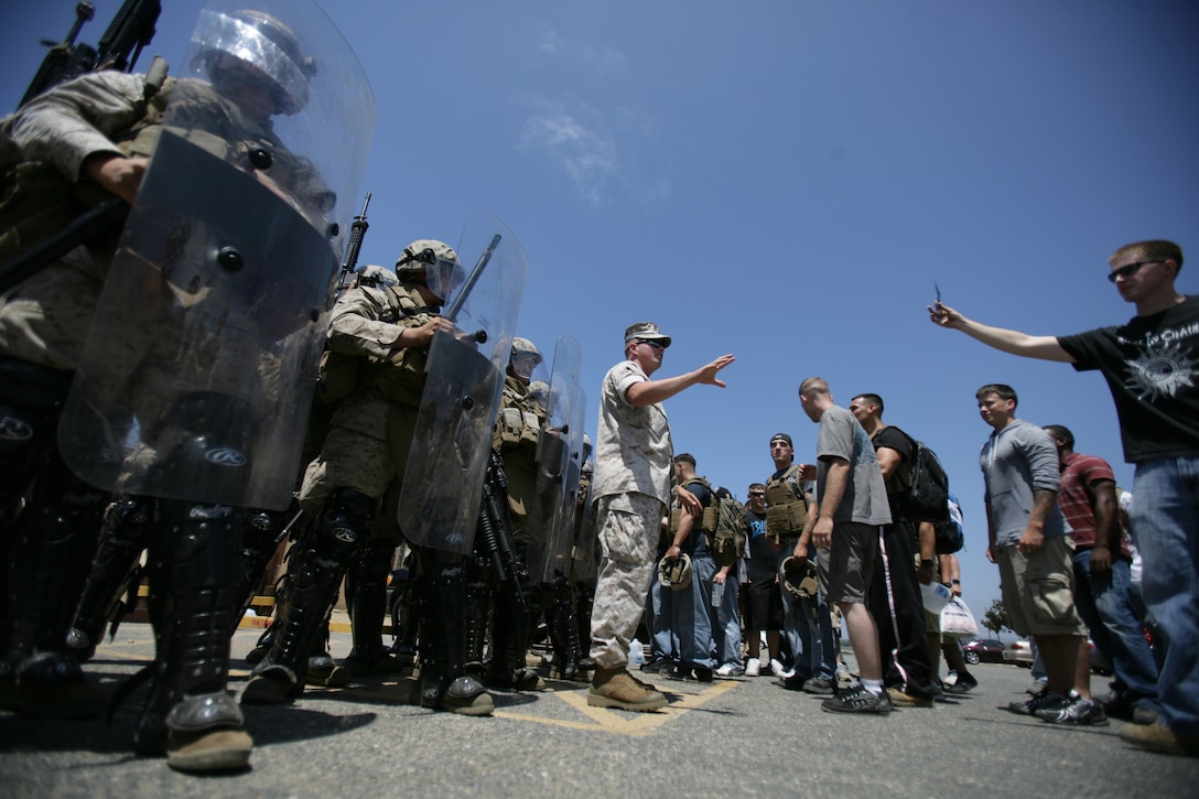 Marines with Battalion Landing Team 2/4 use riot shields to deflect role players during a noncombatant evacuation exercise here July 29. The embassy reinforcement training was conducted to prepare the Marines for a deployment with the 11th Marine Expeditionary Unit later this year.