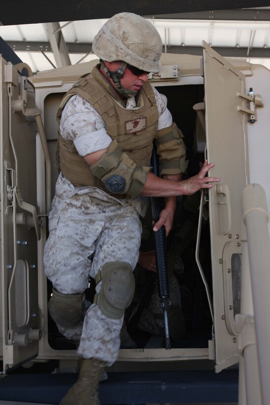 Cpl. Mark Green, a motor transportation operator with Marine Wing Support Squadron 374, opens the back door of the newest rollover training simulator, the Mine Resistant Ambush Protected Egress Trainer, at the Battle Simulation Center at Camp Wilson July 30.