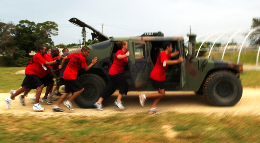 Students from Airman Leadership School reach the end of the course while pushing a Humvee July 27, Kadena Air Base, Japan. The Airmen learn leadership and followership skills as they undergo a course coordinated by the 554th Red Horse Squadron and the Erwin Professional Military Education Center.   (U.S. Air Force photo/Tech. Sgt. Rey Ramon)          