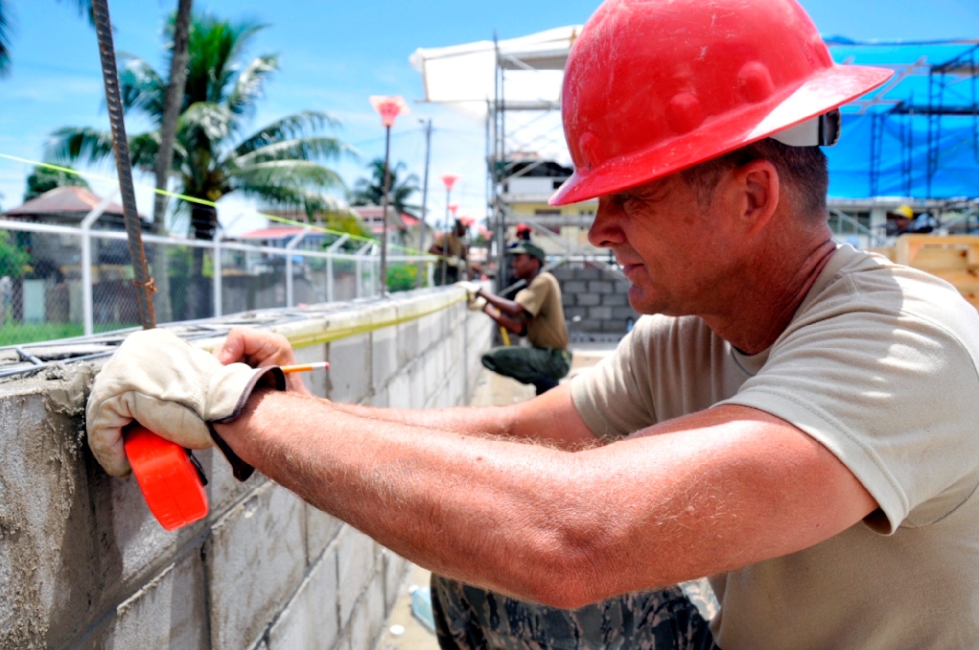 U.S. Air Force Chief Master Sgt. Steve Milhollin, a chief engineer, helps a Guyana Defense Force engineer make block measurements to ensure the joints in a concrete wall stay in line in Georgetown, Guyana, on July 7, 2009. U.S. airmen are participating in New Horizons Guyana, a U.S. Southern Command-sponsored annual exercise designed to strengthen ties with partner nations in Central and South America through combined quality-of-life improvement projects.    DoD photo by Airman 1st Class Perry Aston, U.S. Air Force. (Released)