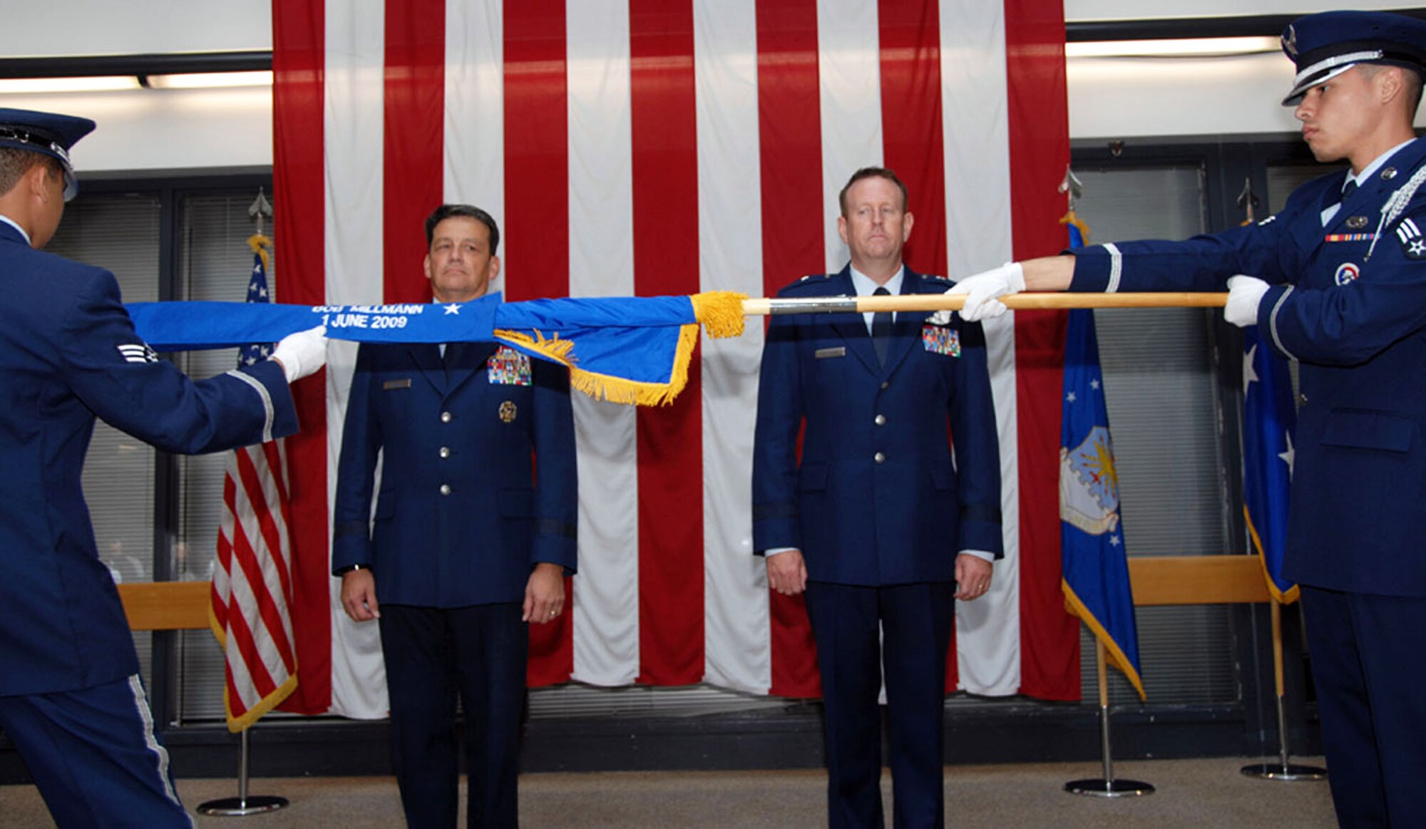 TRAVIS AIR FORCE BASE, Calif. -- The Travis honor guard unfurls Brig. Gen. Robert Millmann’s general officer flag for the first time during Gen Millmann’s “pin-on” ceremony here while Maj. Gen. Frank Padilla and Brig. Gen. Millmann look on. General officers are presented with their own flag upon promotion to O-7. (U.S. Air Force photo/Master Sgt. Robert Wade)