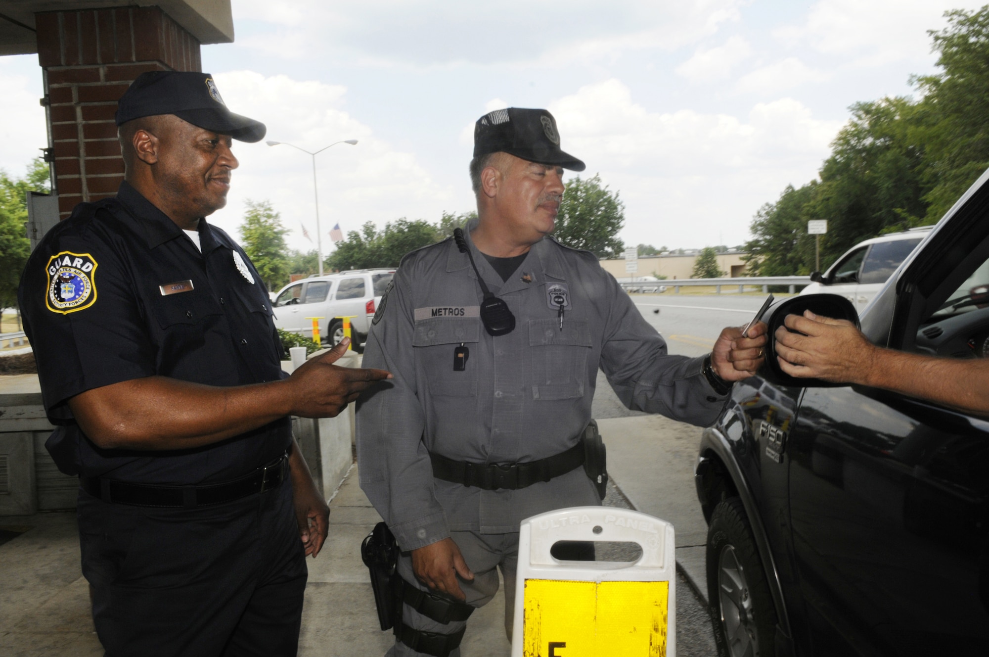 Officers Sanders Harris and Pete Metros, DOD gate guards, check IDs at the Russell Gate July 24. U. S. Air Force photo by Sue Sapp