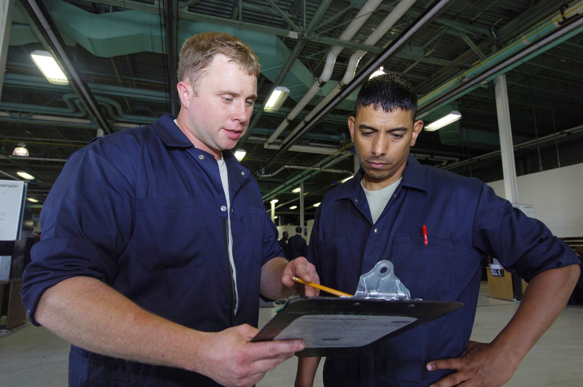 Tech. Sgt. Vincent Hodgdon reviews the daily schedule with Staff Sgt. Esteban Rivera VI July 27 at Minot Air Force Base, N.D. The 5th Maintenance Squadron Aerospace Ground Equipment Flight recently initiated an Air Force Smart Operations for the 21st century process to increase the unit's efficiency to meet the base's mission. The $325 cost investment is expected to yield a return of 60 saved man-hours weekly and more than $1 million annually. Sergeant Hodgdon is the 5th Maintenance Squadron AGE floor leader. (U.S. Air Force photo/Tech. Sgt. Lee A. Osberry Jr.) 
