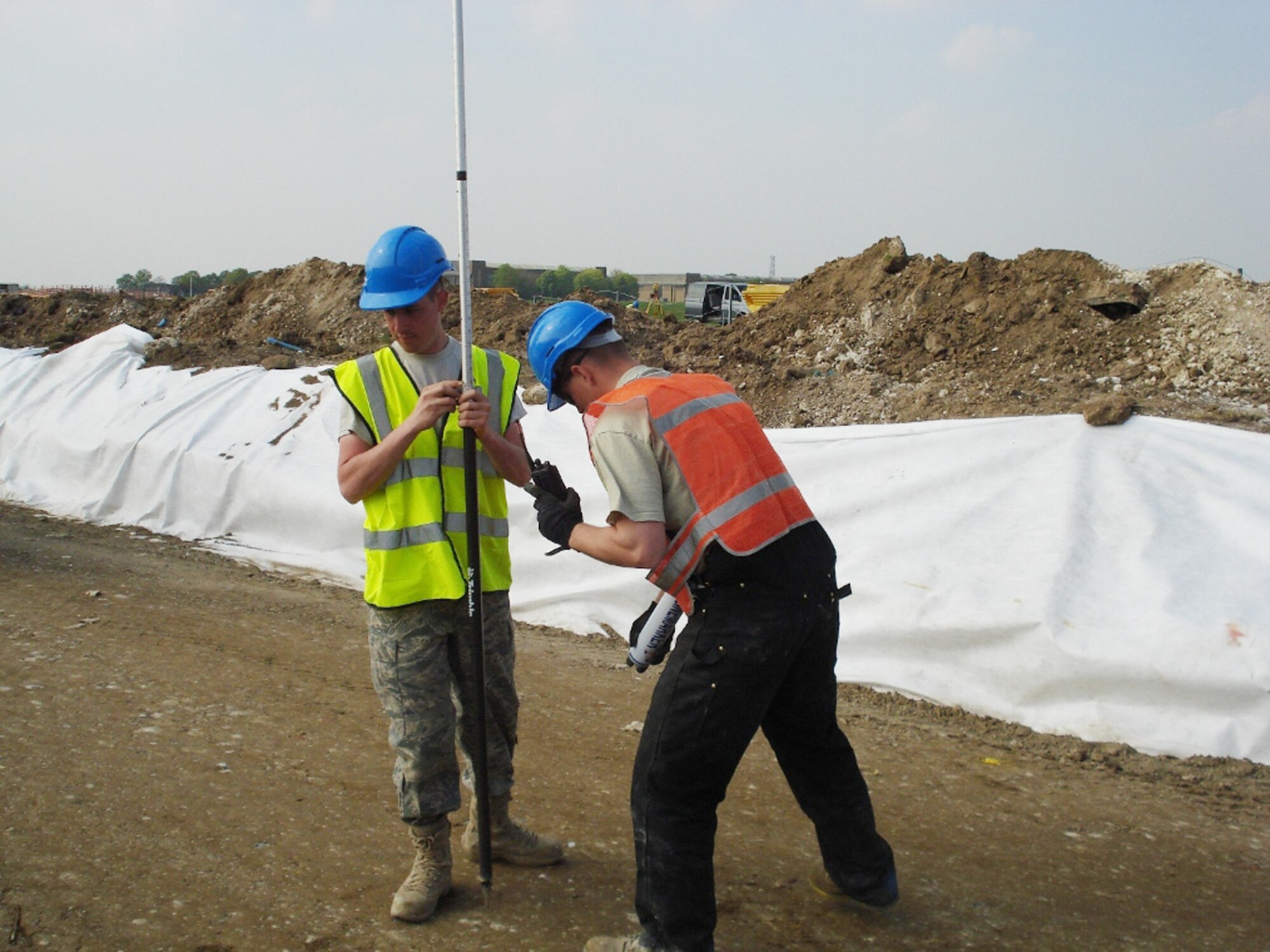 Staff Sgt. Ian Aeppli and Senior Airman Jacob Bailey conduct elevation checks during grading operations for a new perimeter road in July at Royal Air Force Feltwell, England. Sergeant Aeppli is an 86th Construction and Training Squadron Military Construction Flight utilities systems craftsman, and Airman Bailey is an 86th CTS/MCF pavements and equipment operator. (U.S. Air Force photo) 