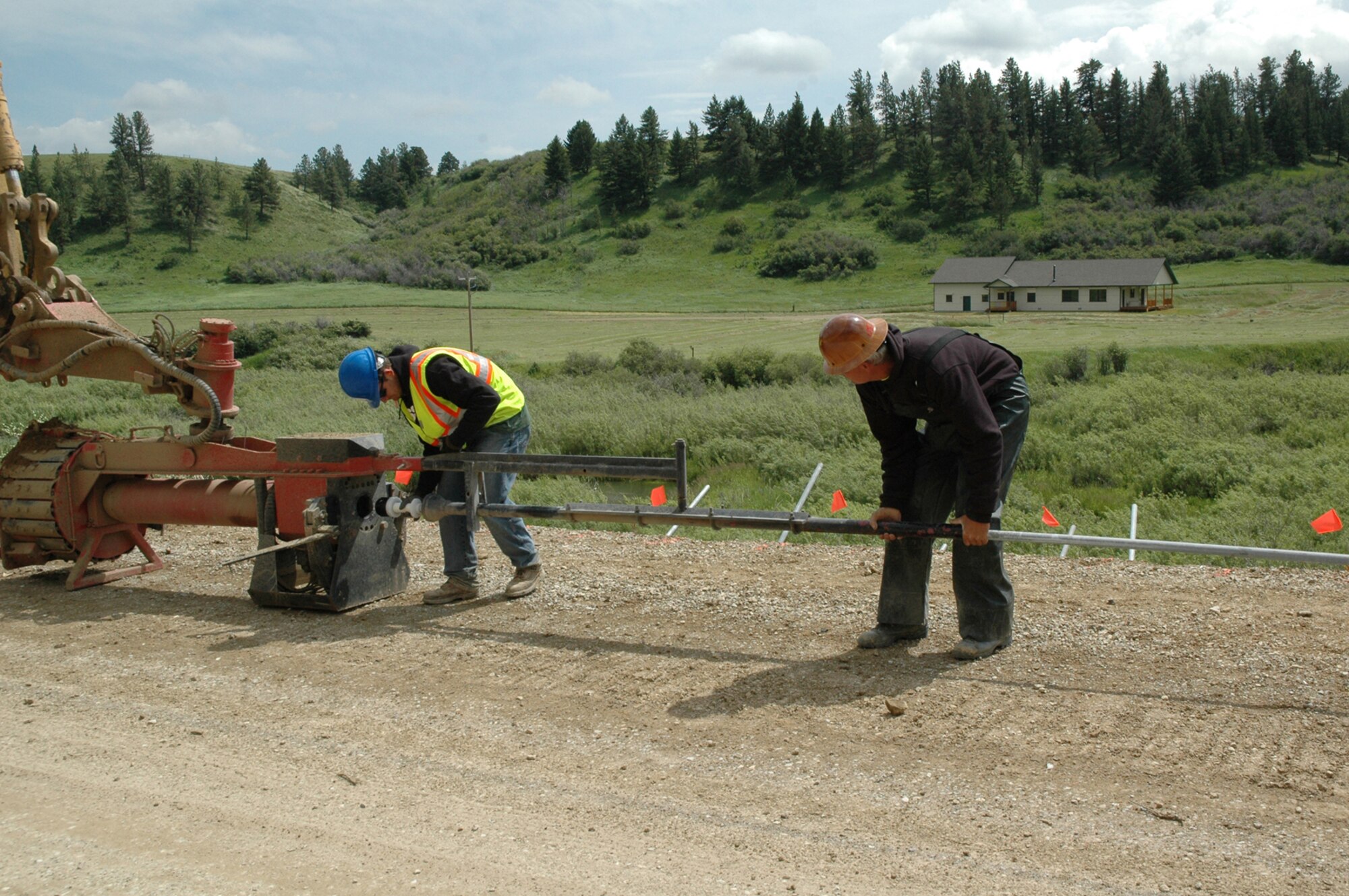Contractors load a steel pipe into the Soil Nail Launcher July 14 on Forest Grove Road near Lewistown, Mont. The launcher fired galvanized steel pipe, called soil nails, into the embankment of the road, where a land slide occurred in May. The nails travel at more than 200 miles per hour into soils to provide anchors for wire mesh and concrete that will prevent further landslides. Since the machine can operate from the roadway, the wetland below was untouched. (U.S. Air Force photo/Senior Airman Dillon White)