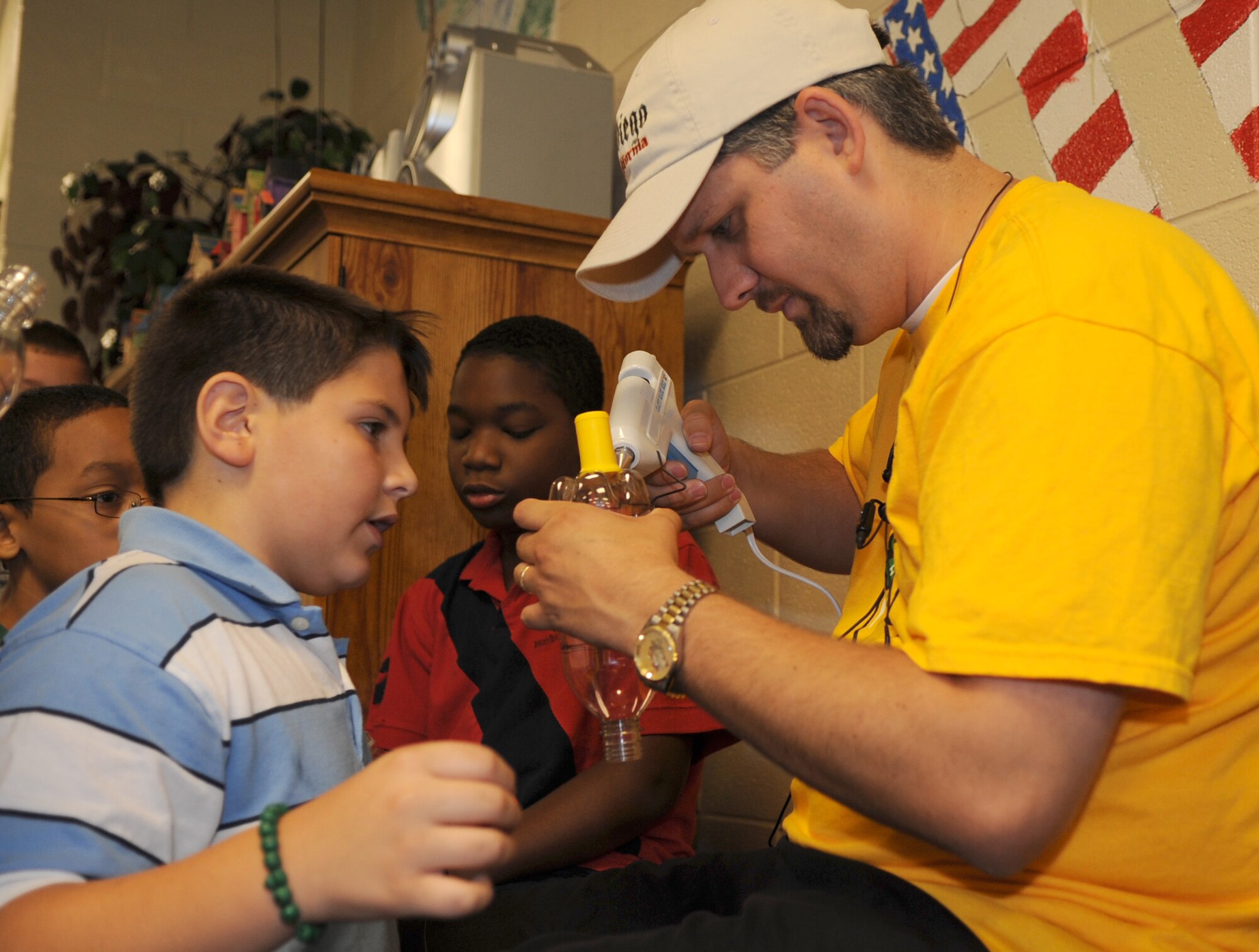 Michael Rigolo, 9, son of Master Sgt. Joseph Rigolo, 2d Aircraft Maintenance Squadron, watches as Eddie Presley, 4-H volunteer, glues the top of the model rocket together. (United States Air Force photo by Senior Airman Alexandra Longfellow) 