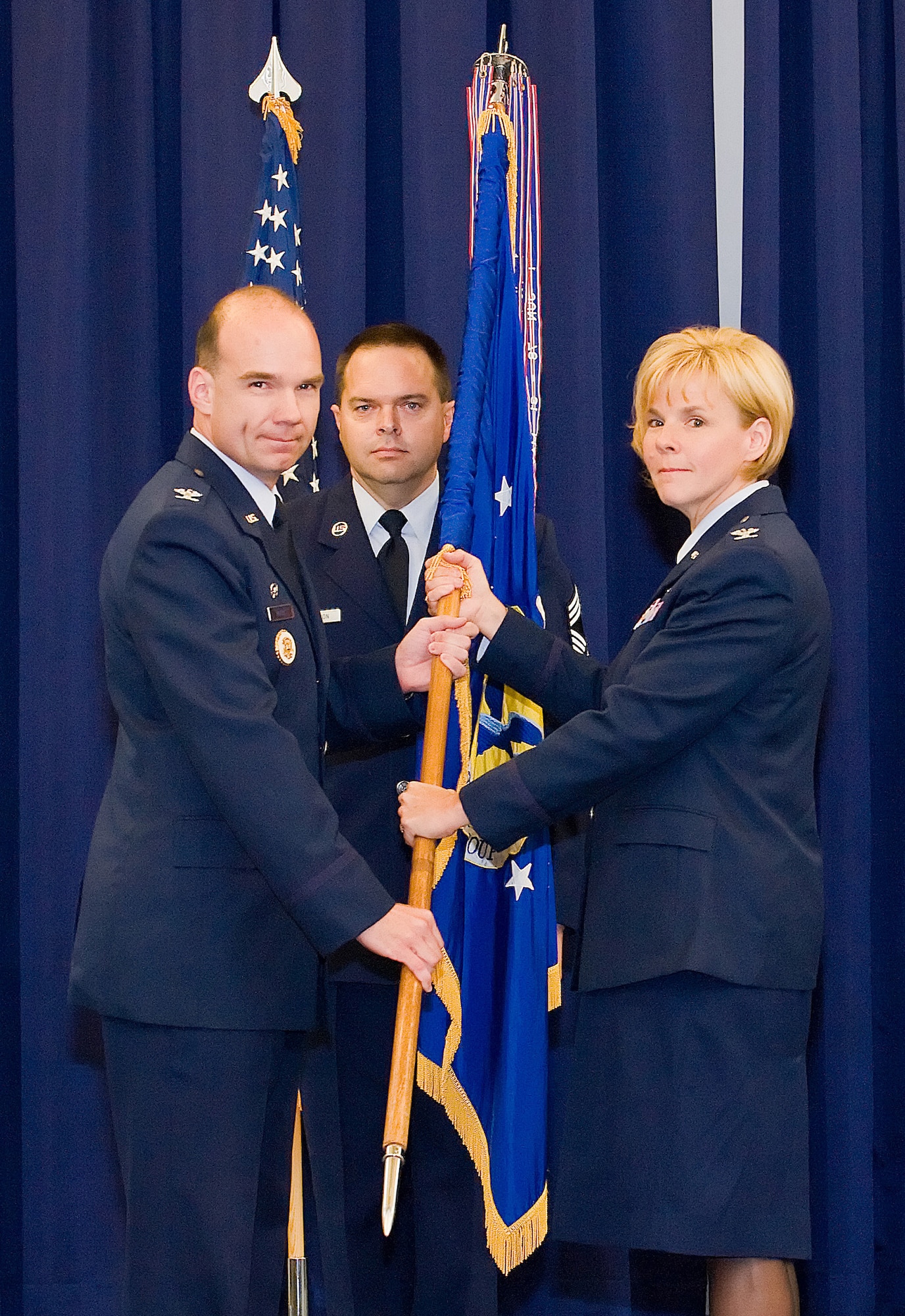 (Left) Col. Manson Morris, 436th Airlift Wing commander, hands the guidon to (Right) Col. Sharon Bannister, who assumed command of the 436th Medical Group July 20 at The Landings Club. (Middle) Chief Master Sgt. Pete Cawthorn, served as the guidon bearer. (U.S. Air Force photo/Tom Randle)
