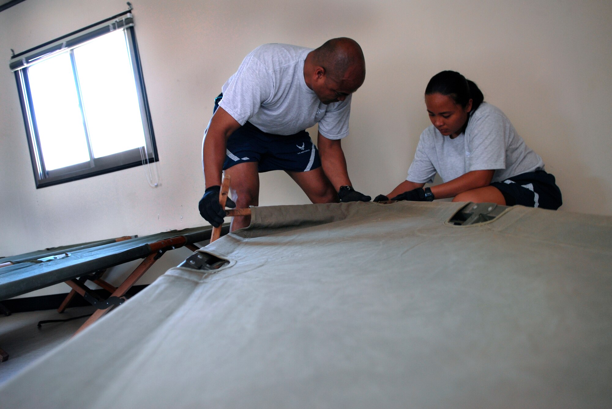 Tent city support personnel unpack and assemble cots in preparation for Ulchi Freedom Guardian, a joint bilateral exercise expected to start in August. More than 550 military members will participate in the exercise. UFG is a regularly scheduled summer exercise involving forces from both the Republic of Korea and the U.S.  These airmen are deployed here from the 254th Force Support Squadron, Andersen Air Base, Guam. (U.S. Air Force photo/Senior Airman Stephenie Wade)

