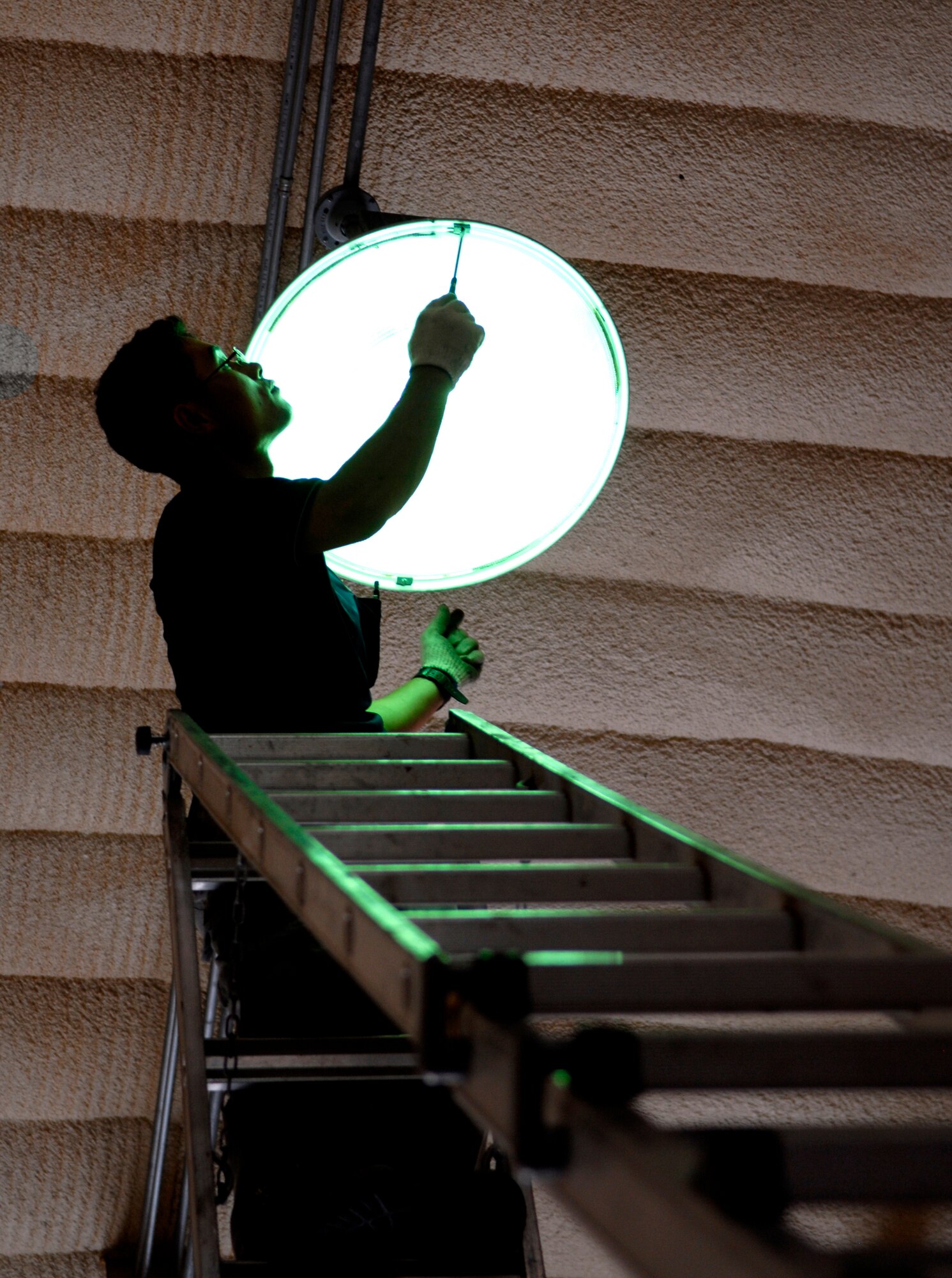 Contract Electrician Konho Yi replaces a metal halide bulb in one of the K-SPAN housing units at Rush Park (tent city) on  Osan Air Base, Republic of Korea July 28. The bulbs are being replaced in preparation for Ulchi Freedom Guardian, a joint bilateral exercise expected to start in August. More than 550 military members will participate in the exercise. UFG is a regularly scheduled summer exercise involving forces from both the Republic of Korea and the U.S. (U.S. Air Force photo/Senior Airman Stephenie Wade)
