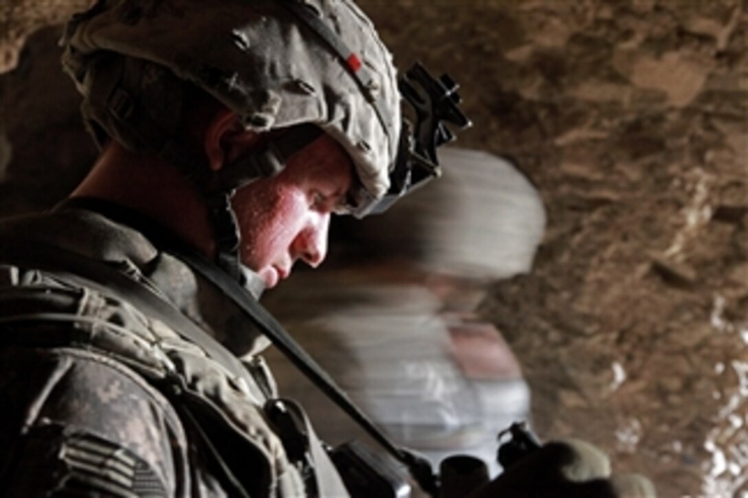U.S. Army Sgt. Stephen Olson observes Afghan National Policemen searching an area of a cave for enemy weapons caches near Shah Wali Zarat, Khowst province, Afghanistan, on July 24, 2009.  Olson is deployed with Alpha Company, 425th Brigade Special Troops Battalion (Airborne), 4th Brigade Combat Team, 25th Infantry Division.  