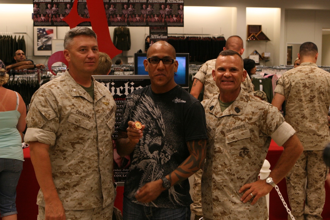Tom Atencio, the vice president of Affliction clothing company displays his coin from Col. Frank A. Richie, the commanding officer of Marine Corps Air Station Miramar at the exchange on base, July 30. Lt. Col. Steven R. Cusumano, the executive officer of the air station, and Sgt. Maj. Roger E. Jenness, the base sergeant major, came to the exchange to thank each fighter and present them with a coin and plaque.