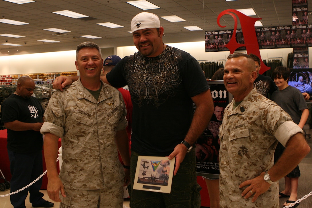 Lt. Col. Steven R. Cusumano, the executive officer of the air station, and Sgt. Maj. Roger E. Jenness, the base sergeant major, presents Tim Sylvia, a former Ultimate Fighting Championship heavyweight with a coin and a plaque from Col. Frank A. Richie, the commanding officer of Marine Corps Air Station Miramar. Affliction clothing company and more than a dozen mixed martial arts fighters visited the exchange on base to meet Marines and sign autographs.