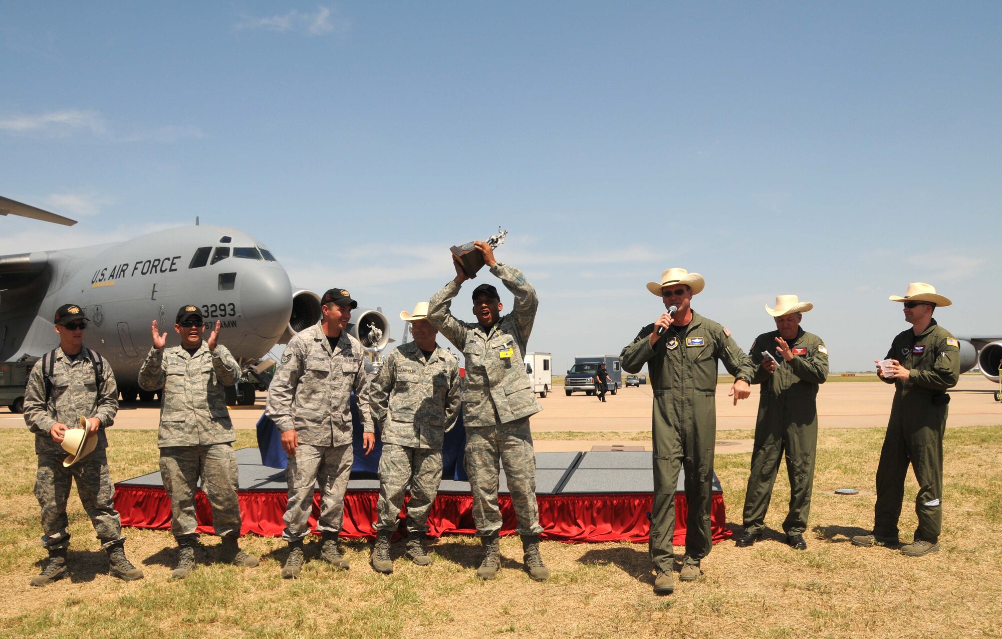 ALTUS AIR FORCE BASE, Okla. -- The Logistics Readiness Squadron team holds their trophy high as Col. Jon "Ty" Thomas, 97th Air Mobility Wing commander, emcees the return home celebration July 25. The LRS team won Best C-17 Engine Running Offload Team during the 2009 Air Mobility RODEO at McChord AFB, Wash., during the week prior. (U.S. Air Force photo/Senior Airman Cherice Bryant)