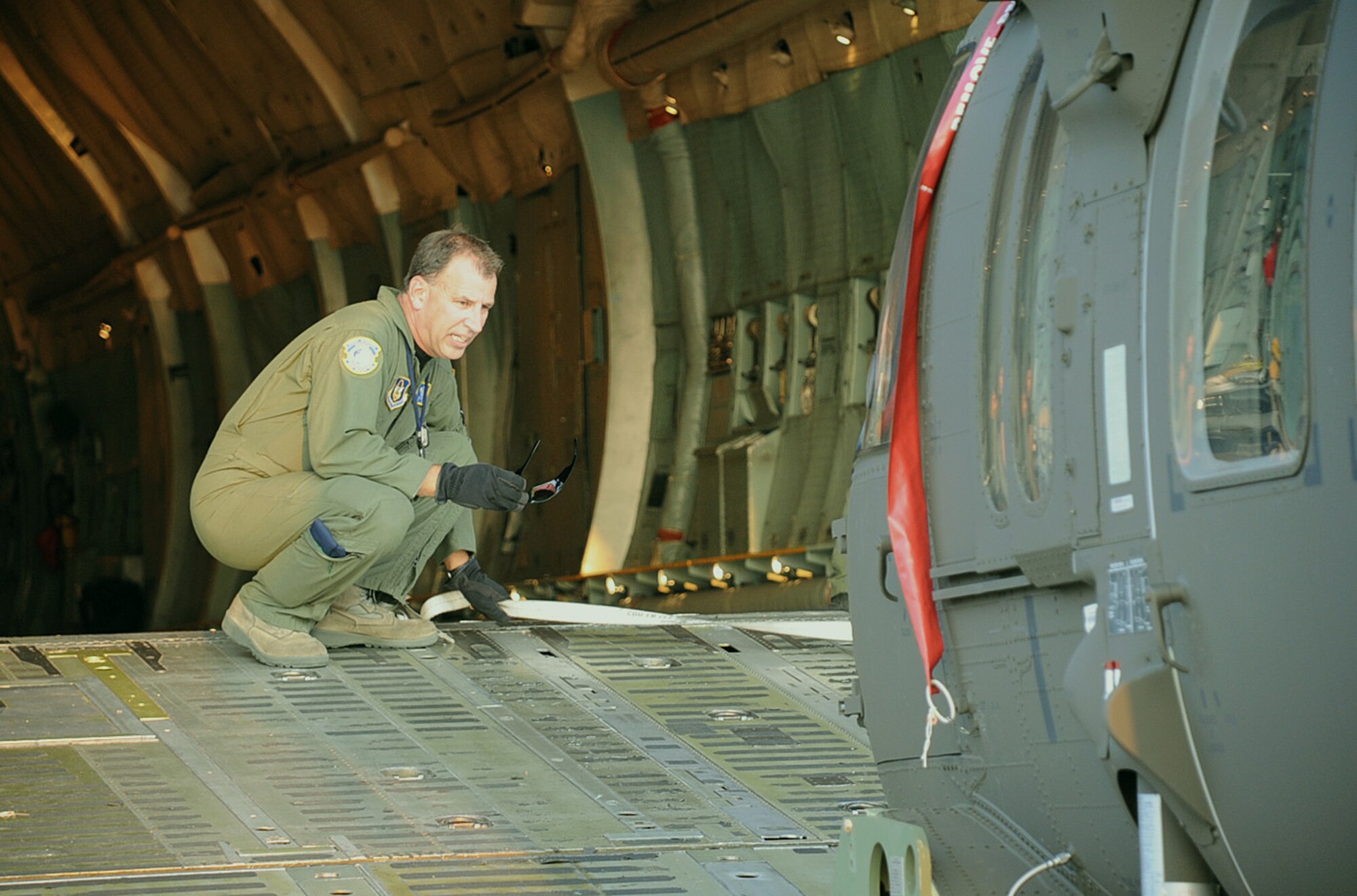Master Sgt. Craig Essert, a loadmaster examiner with the 89th Airlift Squadron at Wright-Patterson Air Force Base, Ohio, ensures a new M-Model UH-60 Blackhawk is clear as a team of Airmen and contractors from Joint Base McGuire-Dix-Lakehurst loads it onto to a C-5Thursday. The team loaded four of the Blackhawks onto the C-5 to transport them to Hawaii where they will replace older models currently used by the Army in the Pacific. (U.S. Air Force photo/Staff Sgt. Danielle Johnson)