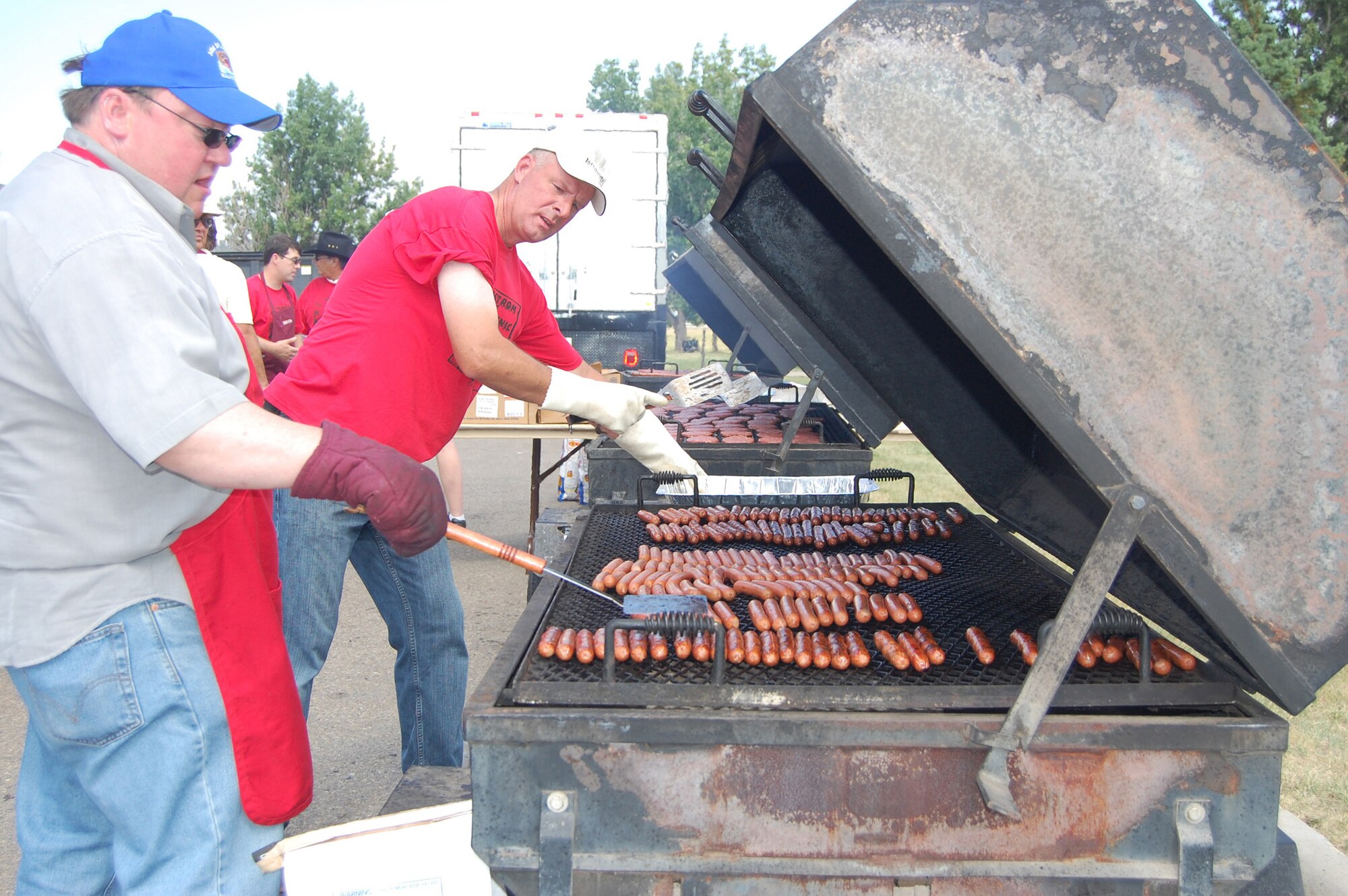 Military Affaris Committee members (left to right) Steve Groom and Mike Croscutt, man the hot dog grill at Sun Plaza Park July 24. The pair cooked 1,000 hot dogs during the annual base picnic the MAC co-sponsors. (U.S. Air Force photo/Valerie Mullett)