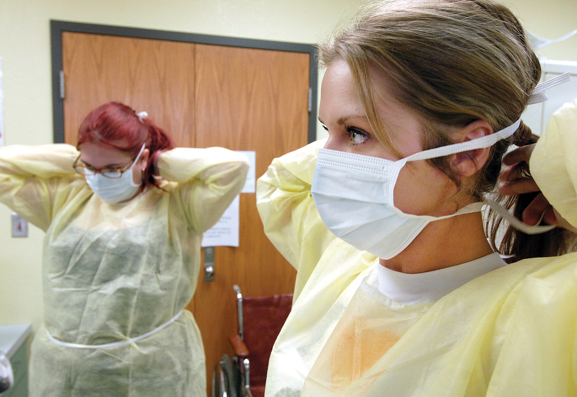 Caitlin Beaty, front, and Kelley Dzik finish dressing in personal protective clothing they might need when performing certified nursing assistant work. The women are students in a new certified nursing assistant training program at the Mid-Del Technology Center in Midwest City. The accelerated class offers portable job skills to spouses of Tinker Airmen. (Air Force photo by Margo Wright)