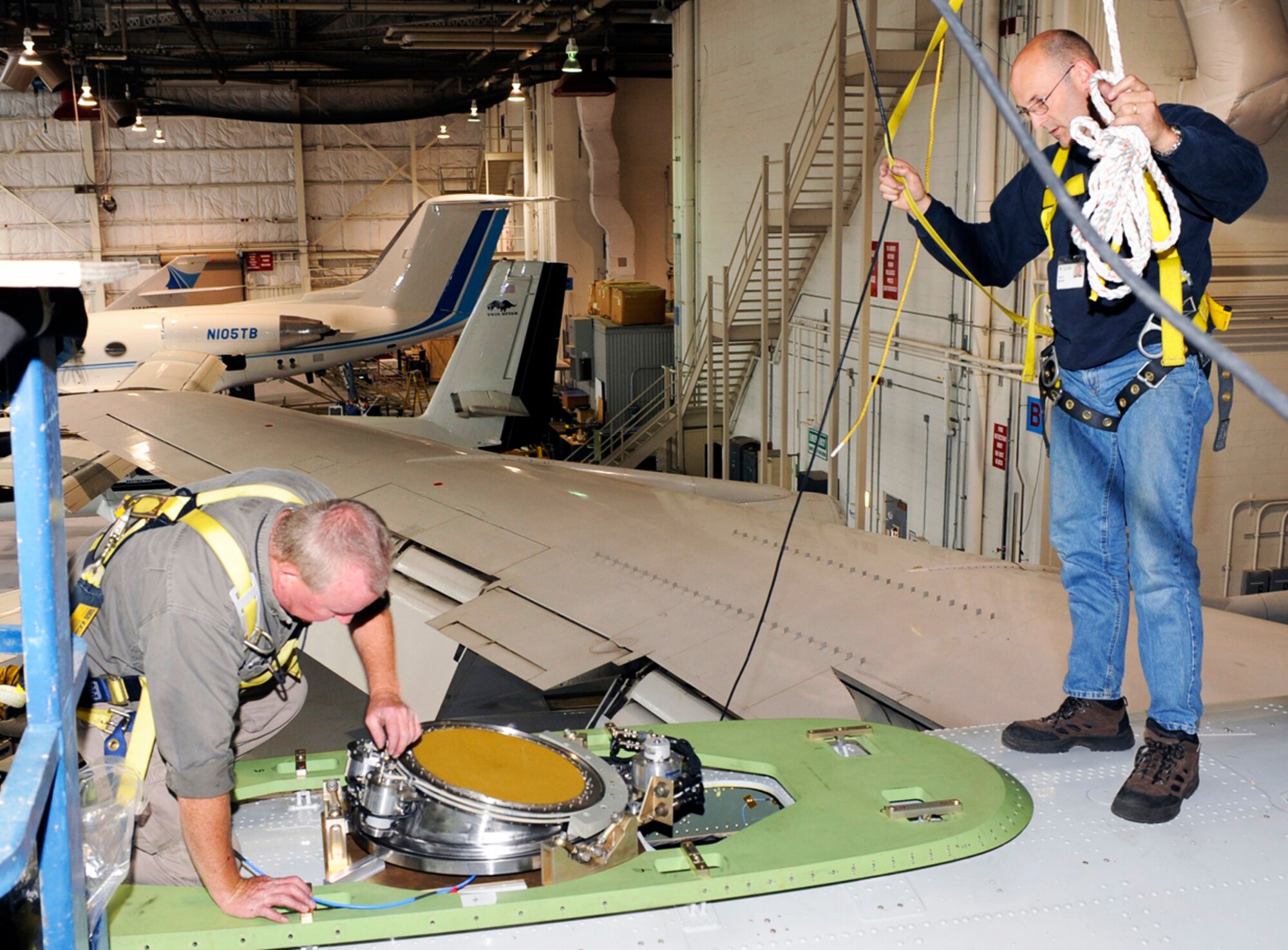Ken Burkett (left) and Dale Morin install the Advanced Multiband Communications Antenna System antenna on the Paul Revere in the Massachusetts Institute of Technology Lincoln Laboratory Flight Facility Building at Hanscom Air Force Base, Mass. Mr. Burkett and Mr. Morin are aircraft mechanics. (Courtesy photo) 