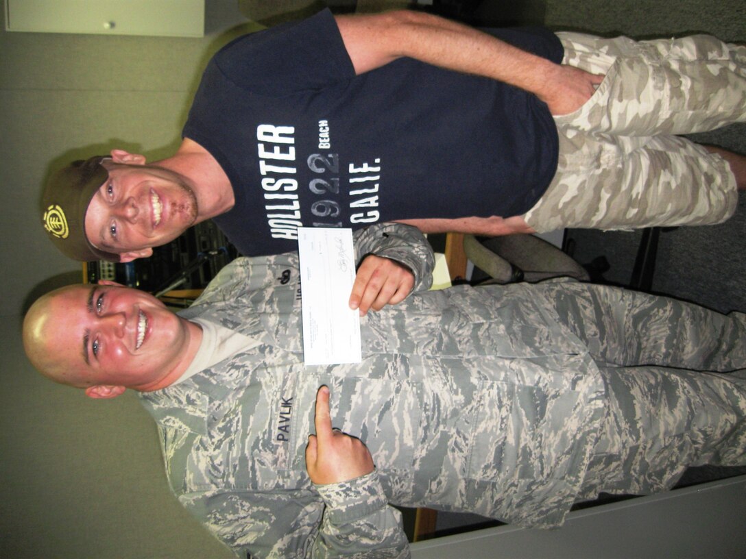 Staff Sgt. Christopher Pavlik, 1st Security Forces Squadron, shows off his check with Jackson, US 106 country music station morning show DJ, after winning $1,500 in Bailout Package contest July 31. Sergeant Pavlik is one of more than 5,000 people who registered for the online contest. (Courtesy Photo/US 106)