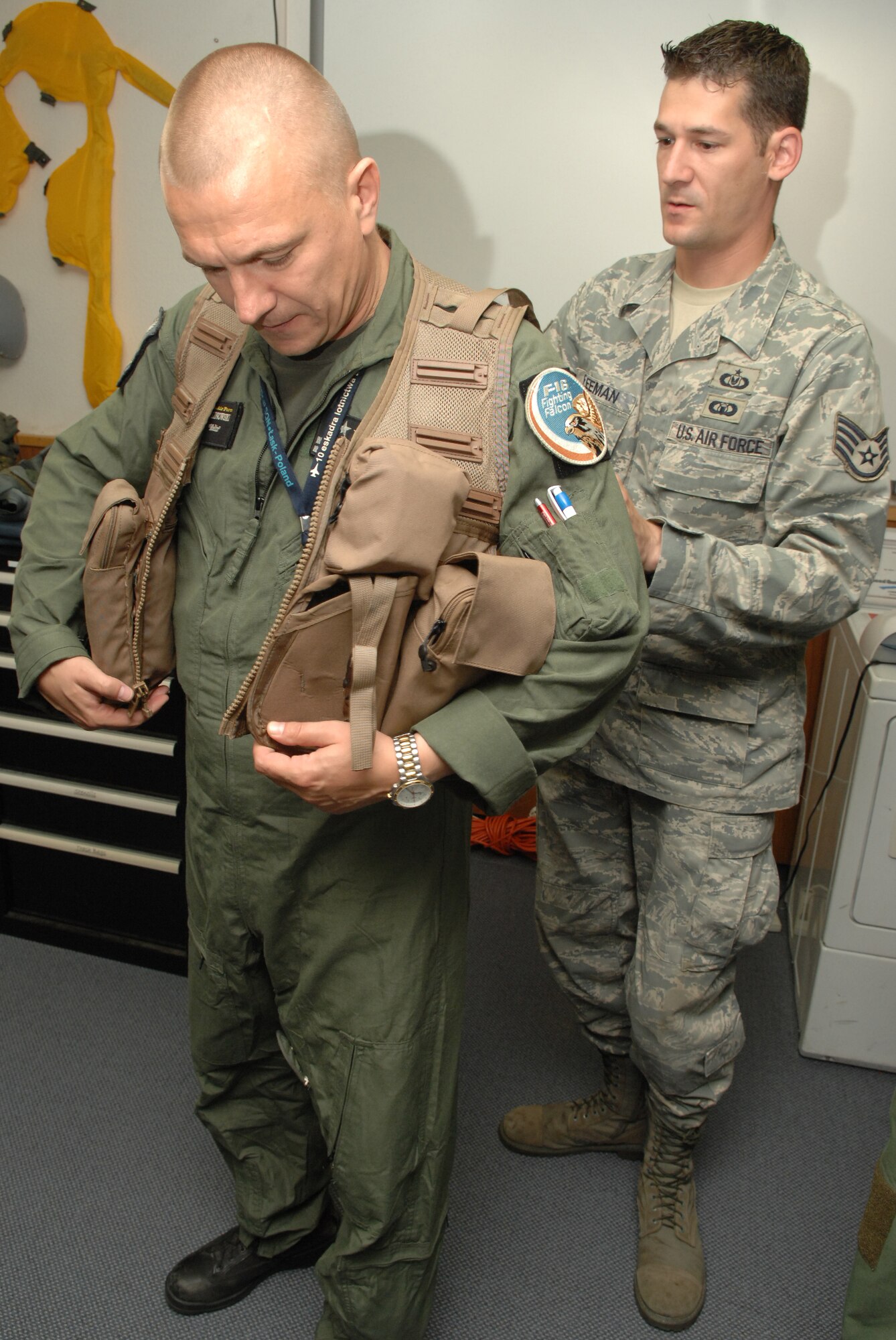 SPANGDAHLEM AIR BASE, Germany - Staff Sgt. Marcus Freeman, 52nd Component Maintenance Squadron, helps Lt. Col. Dariusz Malinowski, 10th Fighter Squadron commander, Lask Air Base, Poland, try on a survival vest during his visit to Spangdahlem Air Base July 29. Four Polish air force members visited Spangdahlem to observe the daily routine and operations tempo of an American F-16 Fighting Falcon squadron and an American air base. (U.S. Air Force photo by Airman 1st Class Nick Wilson)