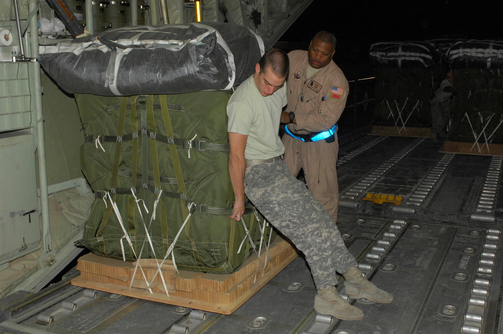 BAGRAM AIRFIELD, Afghanistan - Army Specialist Joshua Vazquez, 612th Port Master Detachment, helps Senior Master Sgt. Timothy Gaines, 165th Airlift Wing, Georgia Air National Guard move a pallet onto a C-130 Hercules cargo bay. The duo were loading the Hercules for an airdrop mission. Specialist Vazquez is deployed from Fort Bragg, N.C., and hails from El Centro, Calif. Sergeant Gaines' unit is deployed from Savannah Ga., which is also his homeown. (U.S. Air Force photo/Tech. Sgt. John Jung)