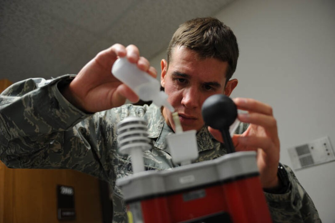 Airman 1st Class Forrest Collins, 28th Medical Group bioenvironmental engineer technician, examines heat-stress readings on a wet-bulb globe thermometer used to determine the work and rest cycles for outside workers here, July 29. The wet-bulb globe thermometer measures heat stress by combining humidity, radiant heat and dry heat into one reading. (U.S. Air Force photo/Airman 1st Class Adam Grant)