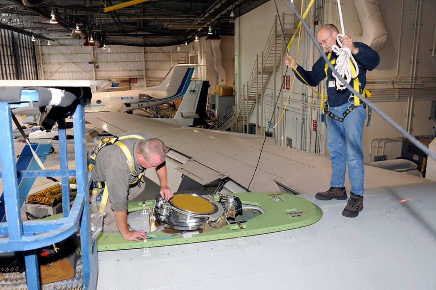 Aircraft mechanics Ken Burkett (left) and Dale Morin install the AMCAS antenna on the Paul Revere in the MIT’s Lincoln Laboratory Flight Facility Building at Hanscom. (Courtesy photo) 
