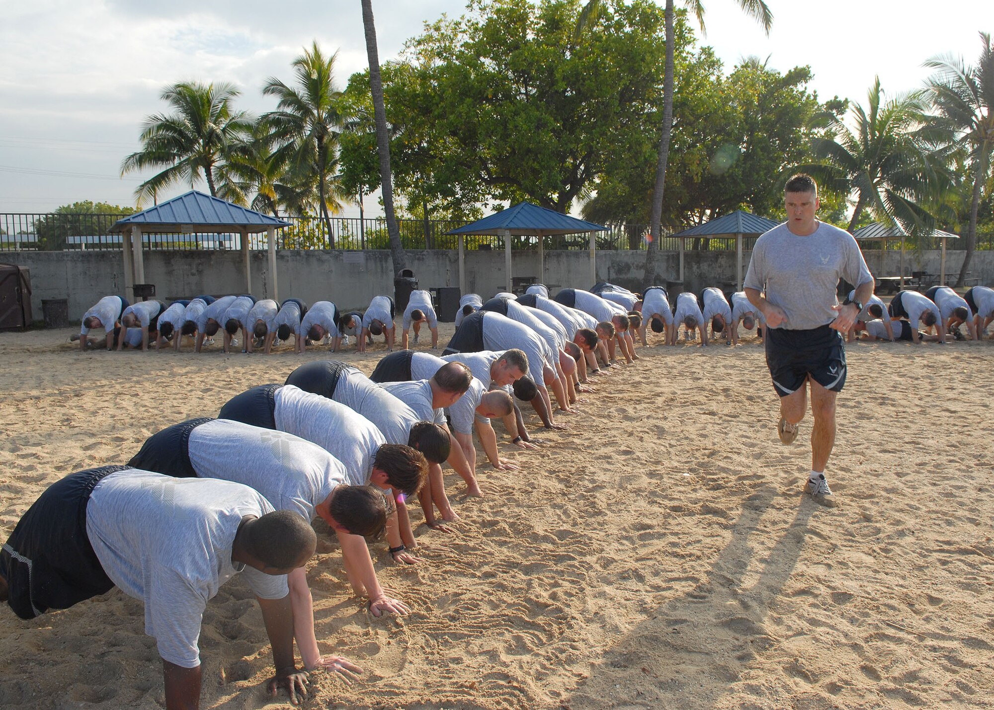 Chief Master Sgt. Scott Delveau, Pacific Air Forces first sergeant, leads the formation of a “human tunnel” during a morning beach physical training session May 27 at Hickam Air Force Base, Hawaii. Approximately 70 people participated in the physical training session, which included a 1.5-mile run to Hickam Beach, a half-hour session of calisthenics and team building, followed by a 1.5-mile run back to the starting point. The directorates participating in the beach session were A3, A4, A5 and A8. (U.S. Air Force photo/Tech. Sgt. Jerome Tayborn)