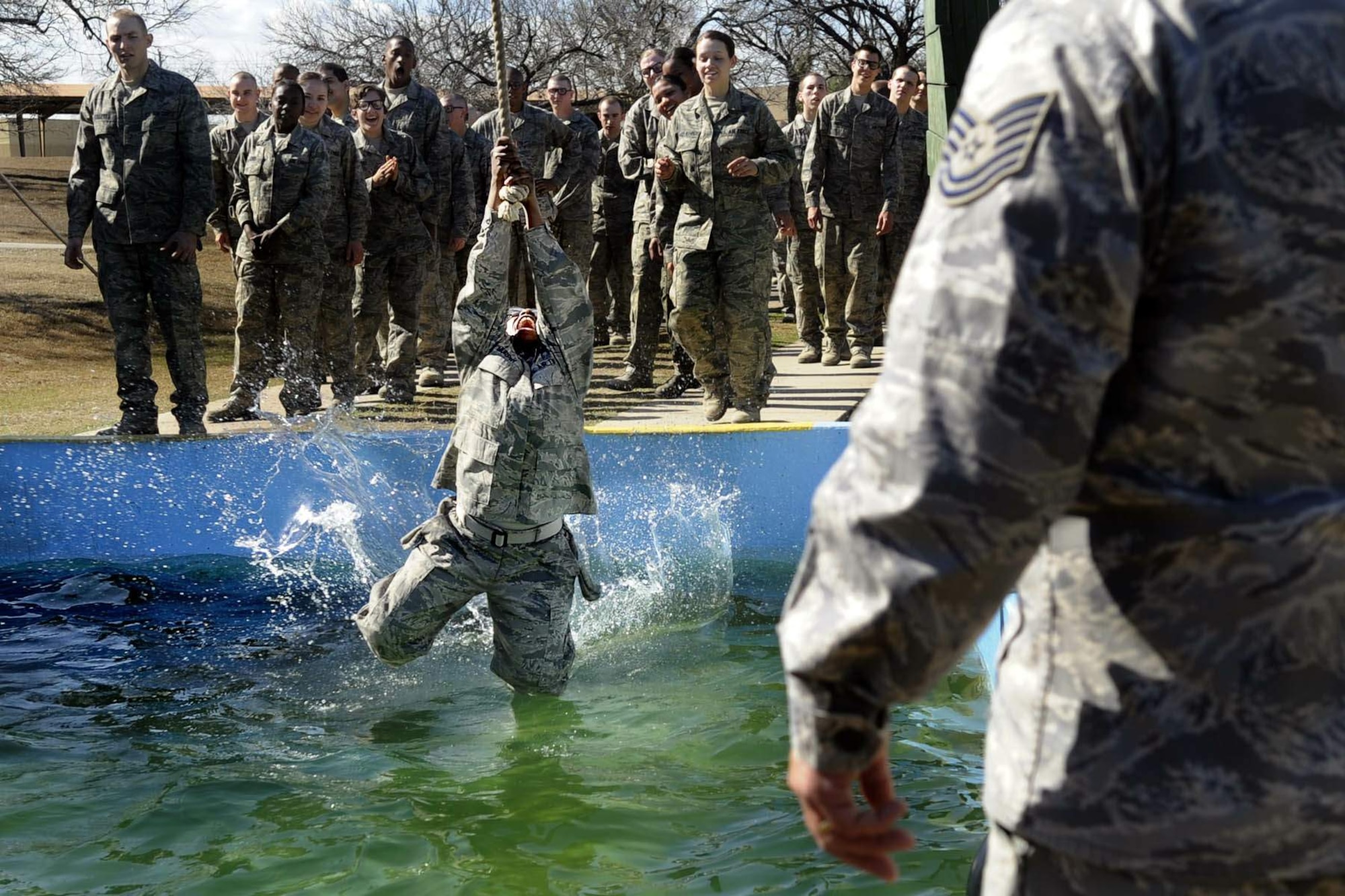 A basic trainee swings across a cold water pool as her knees get wet at the obstacle course. A military training instructor stands on the far side of the pool to assist. A recently expanded Air Force Basic Military Training program focuses on a ?warrior first? philosophy. (U.S. Air Force photo/Master Sgt. Cecilio Ricardo)
