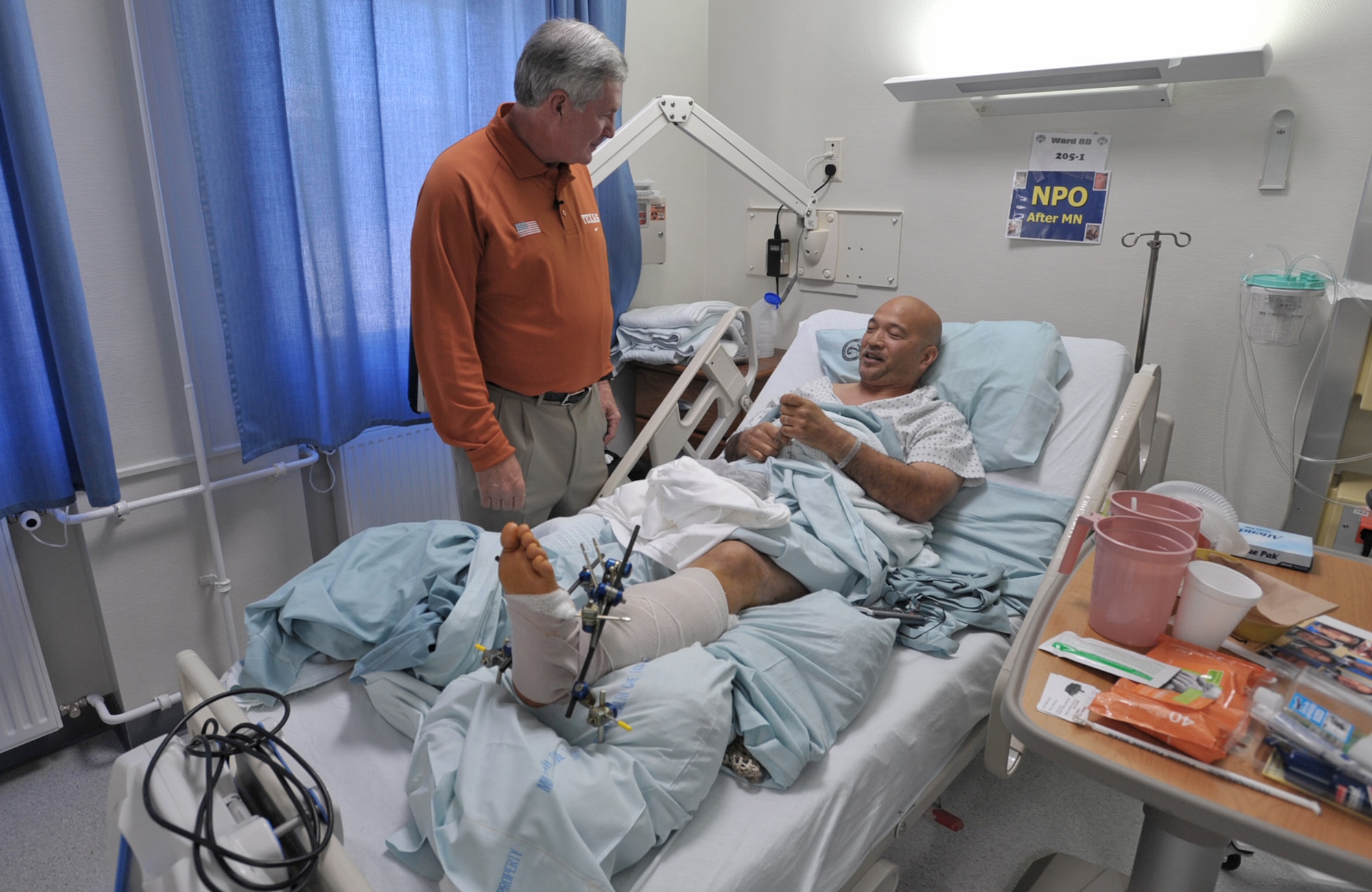 University of Texas Coach Mack Brown visits with Henry Bautista at a U.S. military hospital May 29 in Landstuhl, Germany. The hospital was one of the first stops for Coaches Tour 2009, a morale-boosting mission that brings NCAA football coaches to U.S. servicemembers and their families. Mr. Bautista served 10 years in Army intelligence without any major injuries before he became a civilian field representative for an armored vehicle contractor. He was flown to Germany from Iraq after his leg was severely injured by a mishap with one of the vehicles. (U.S. Air Force photo/Tech. Sgt. Jason Schaap)
