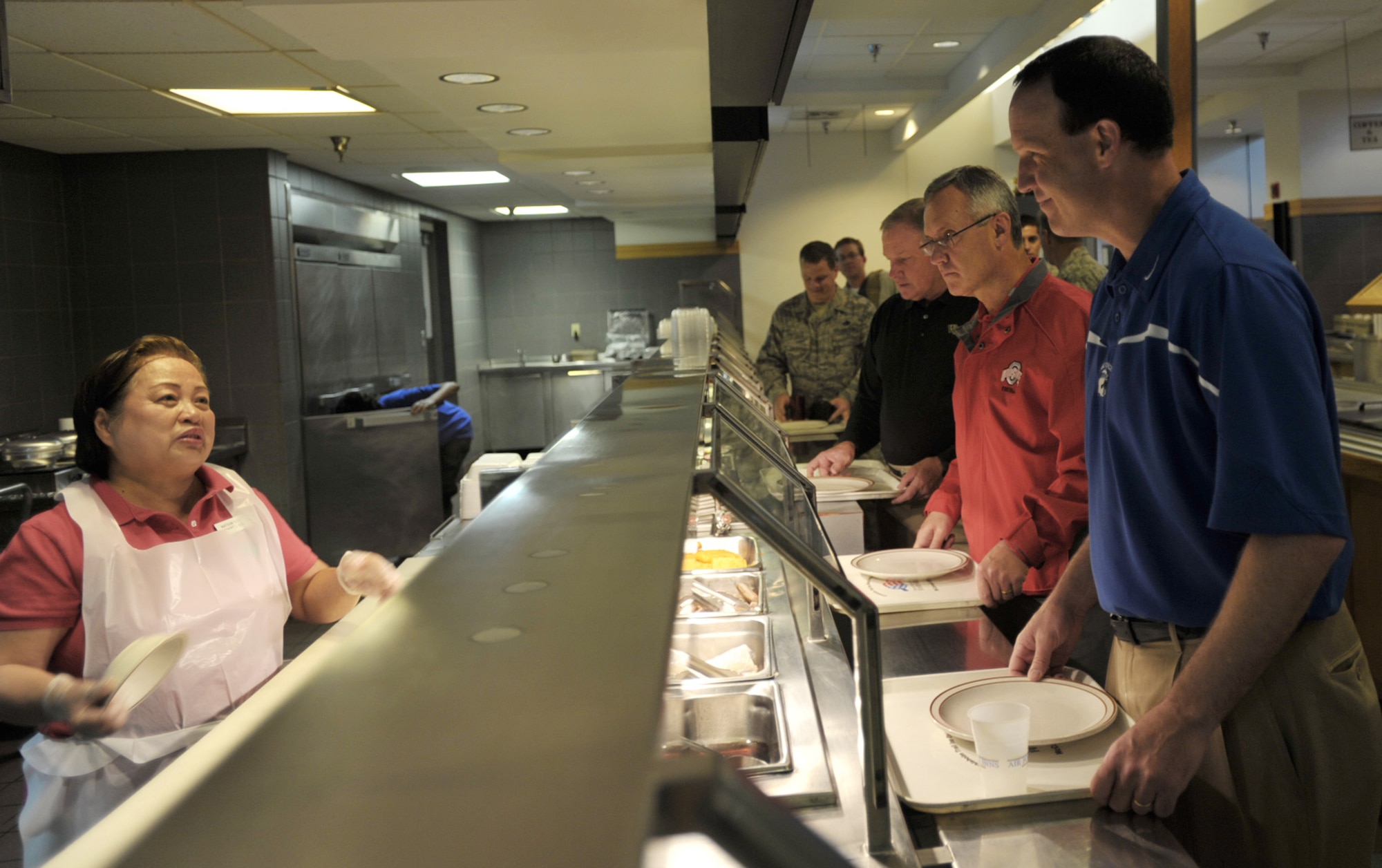 Air Force Coach Troy Calhoun of Air Force (in blue), Ohio State Coach Jim Tressel (in red) and Wake Forest Coach Jim Grobe (in black) tell Teresita Walline what they would like for breakfast May 28 at Ramstein Air Base, Germany. Walline is a mess attendant at the base dining facility, where the coaches soon after attended a breakfast with active-duty, Reserve and Air National Guard Airmen. (U.S. Air Force photo/Tech. Sgt. Jason Schaap)