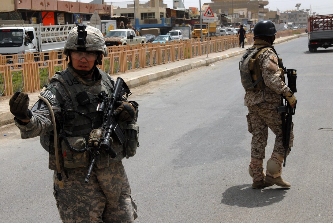 U.S. Army Staff Sgt. Joseph Lopez stops traffic as an Iraqi army soldier secures the other direction while on patrol in Sadr City, Iraq, May 27, 2009. Lopez is an infantryman section leader assigned to the 1st Cavalry Division's Company B, 2nd Battalion, 5th Cavalry Regiment, 1st Brigade Combat Team.
