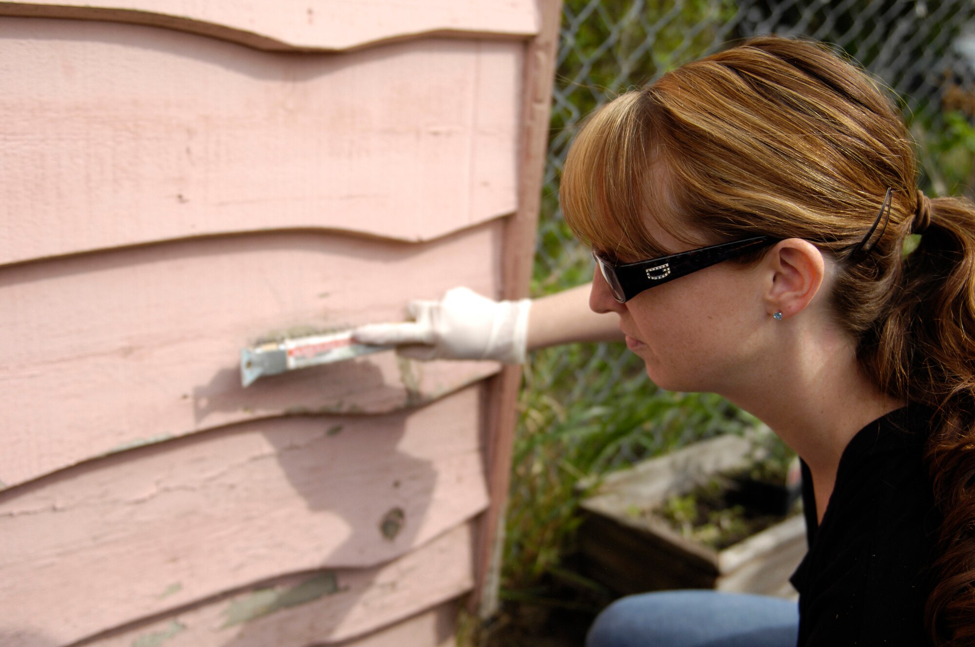 ELMENDORF AIR FORCE BASE, Alaska -- Tech. Sgt. Crystal Trevino, FTAC Instructor, scrapes paint from a local Anchorage home in efforts with the Volunteer Action Council and their Paint the Town project. The Paint the Town campaign is a volunteer project that will restore the exterior of 25 local homes with a new coat of paint.(U.S. Air Force/Senior Airman Stephen Patrick)