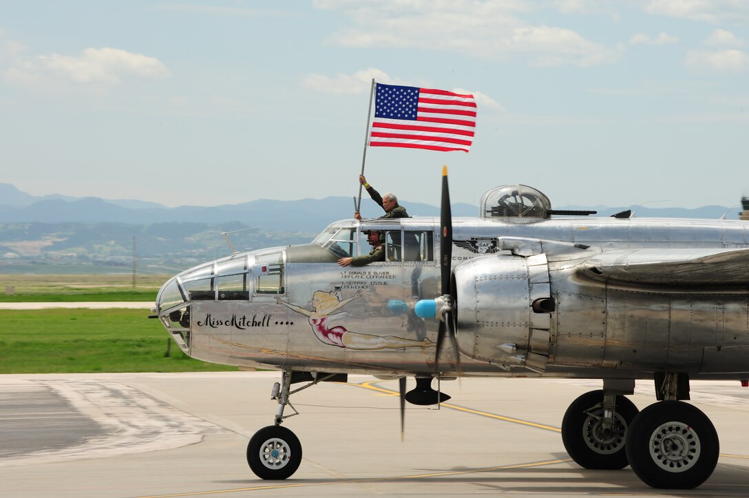 Aircrew members of the B-25 Mitchell taxi across the flightline while waving the American flag during the 2009 Dakota Thunder open house and air show here, May 30.  The B-25 was just one of many aircrafts to dazzle the crowds during the air show. (U.S. Air Force photo/Senior Airman Anthony Sanchelli)